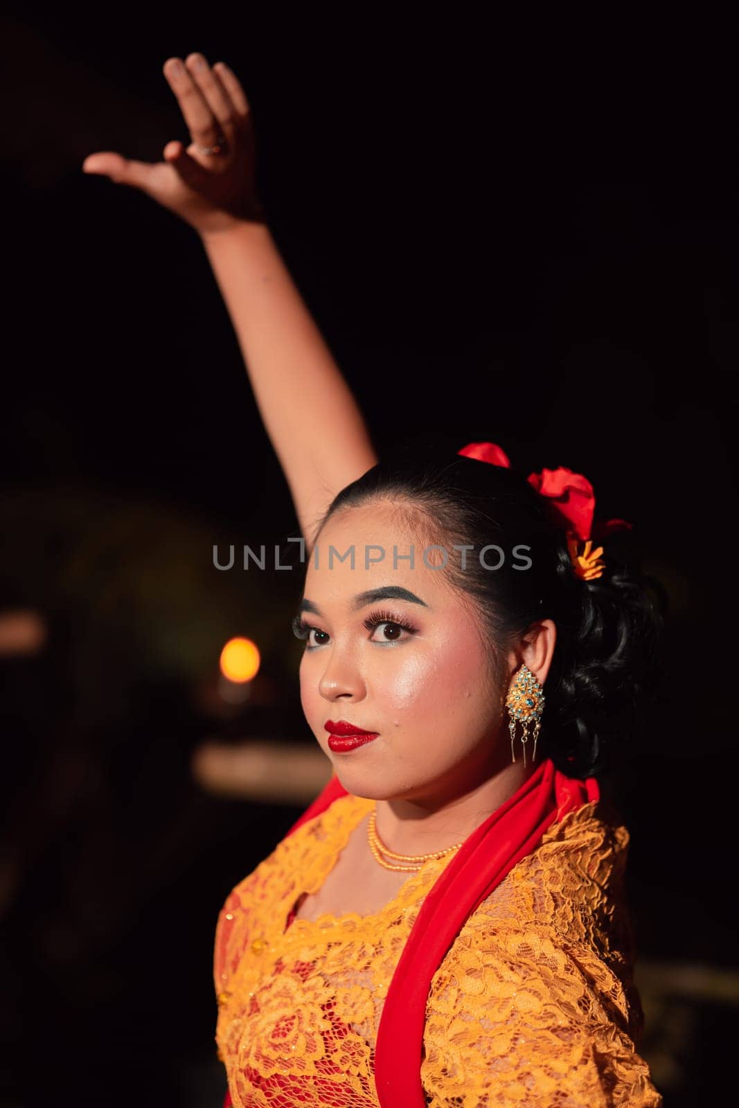 The beautiful closeup face of a Javanese woman with make-up at a traditional dance performance while wearing a yellow costume in the village