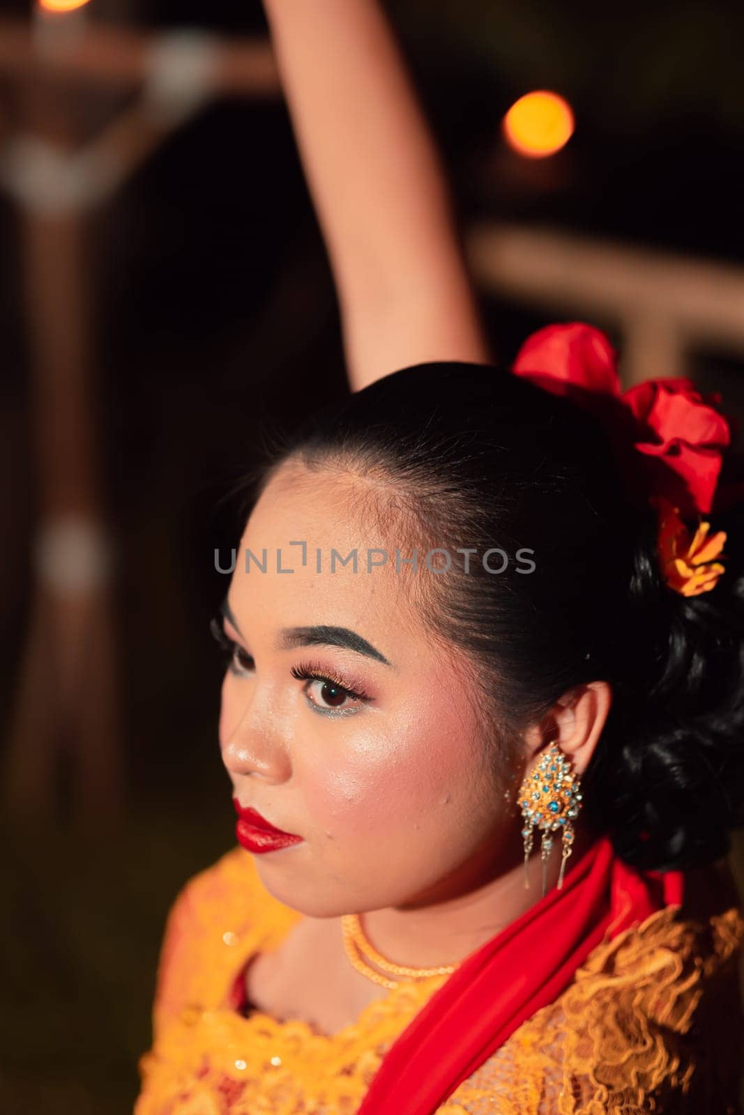 The beautiful closeup face of a Javanese woman with make-up at a traditional dance performance while wearing a yellow costume in the village