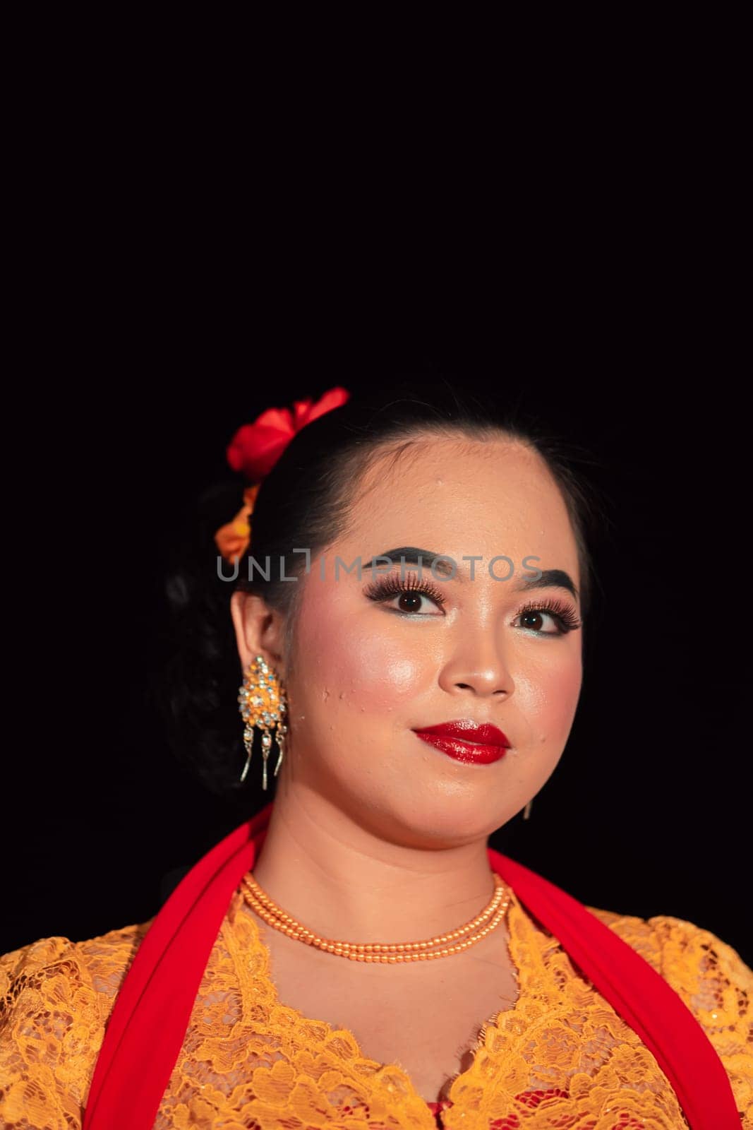 Sundanese woman wearing a short dress and traditional yellow dress with red scarf and makeup after the dance performance on the stage
