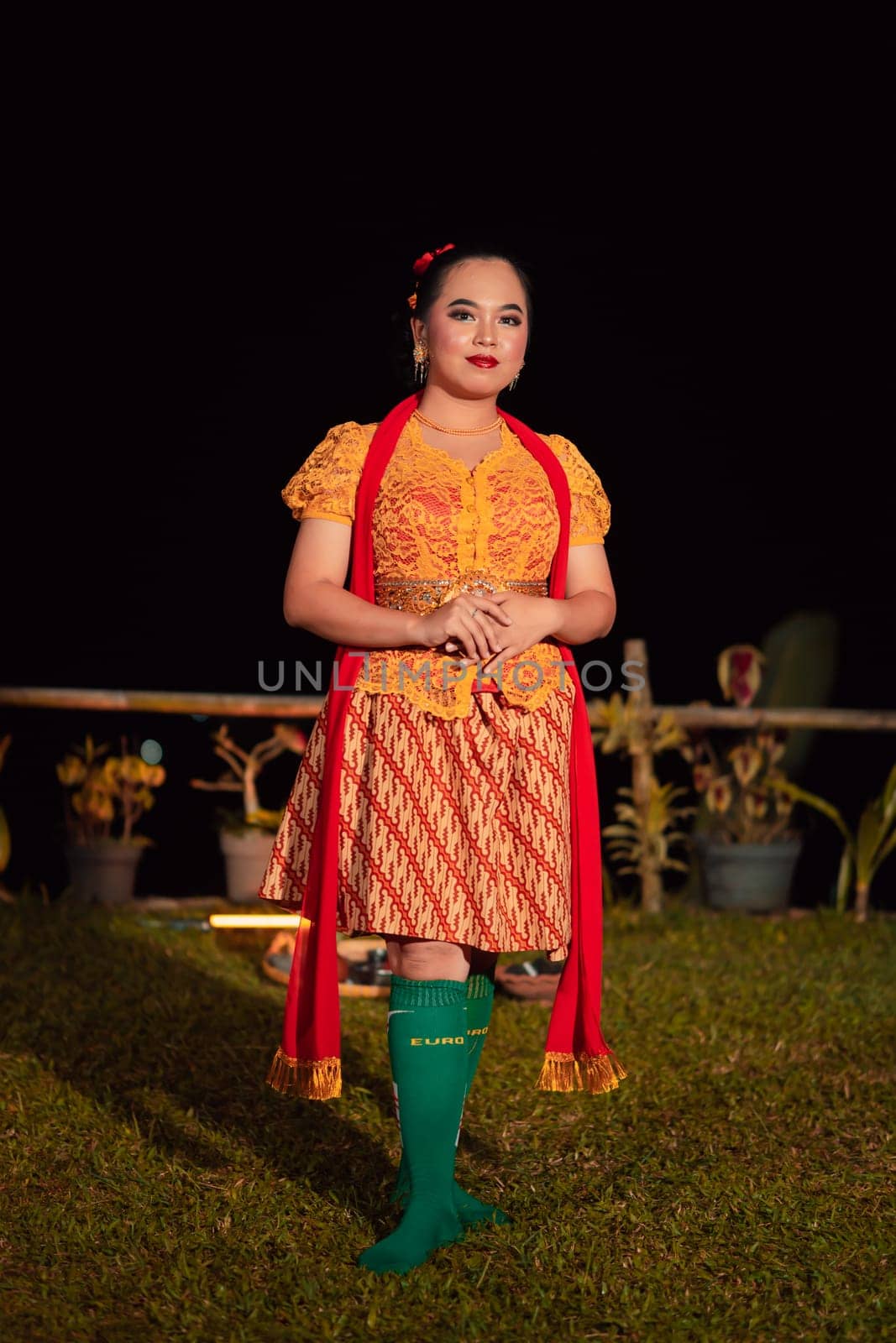 Sundanese woman wearing a short dress and traditional yellow dress with red scarf and makeup after the dance performance on the stage