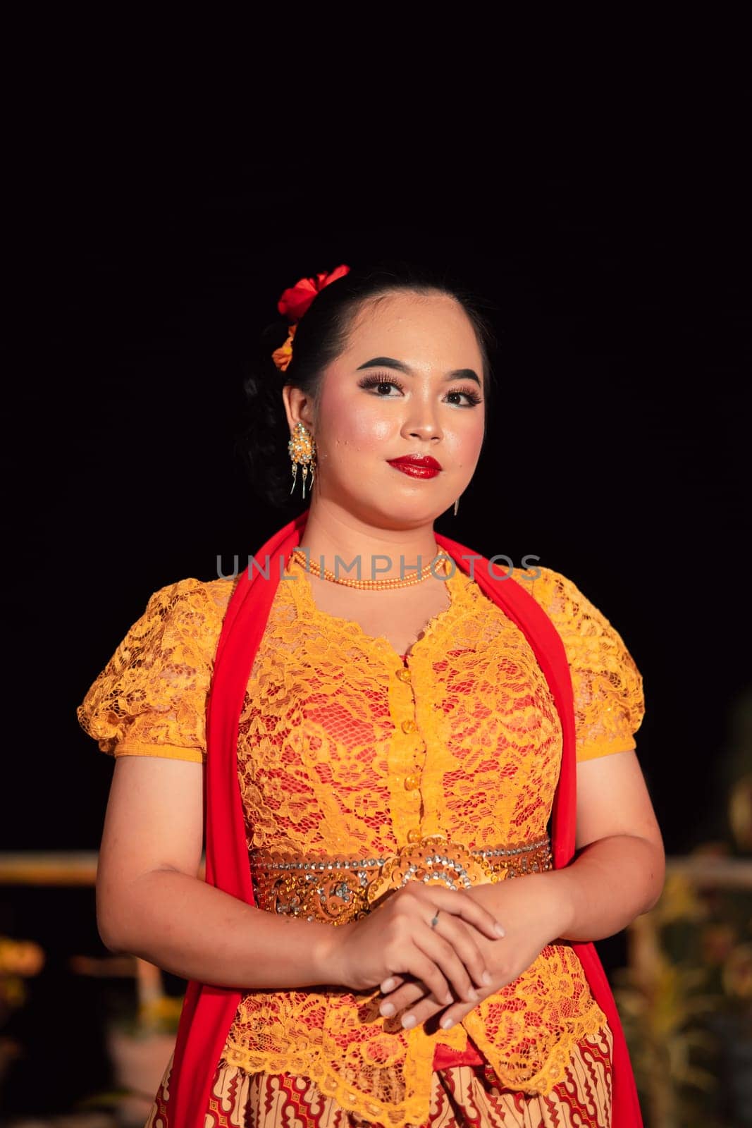 Sundanese woman wearing a short dress and traditional yellow dress with red scarf and makeup after the dance performance on the stage