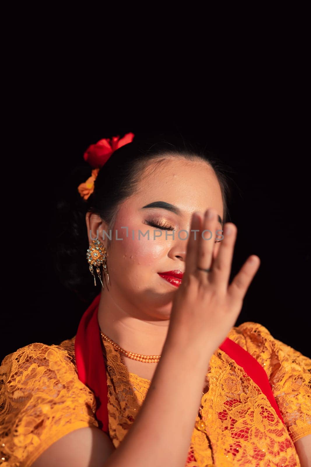 Beautiful face of an Asian woman with red lips and makeup in Indonesian traditional dance costume after the dance performance in the stage