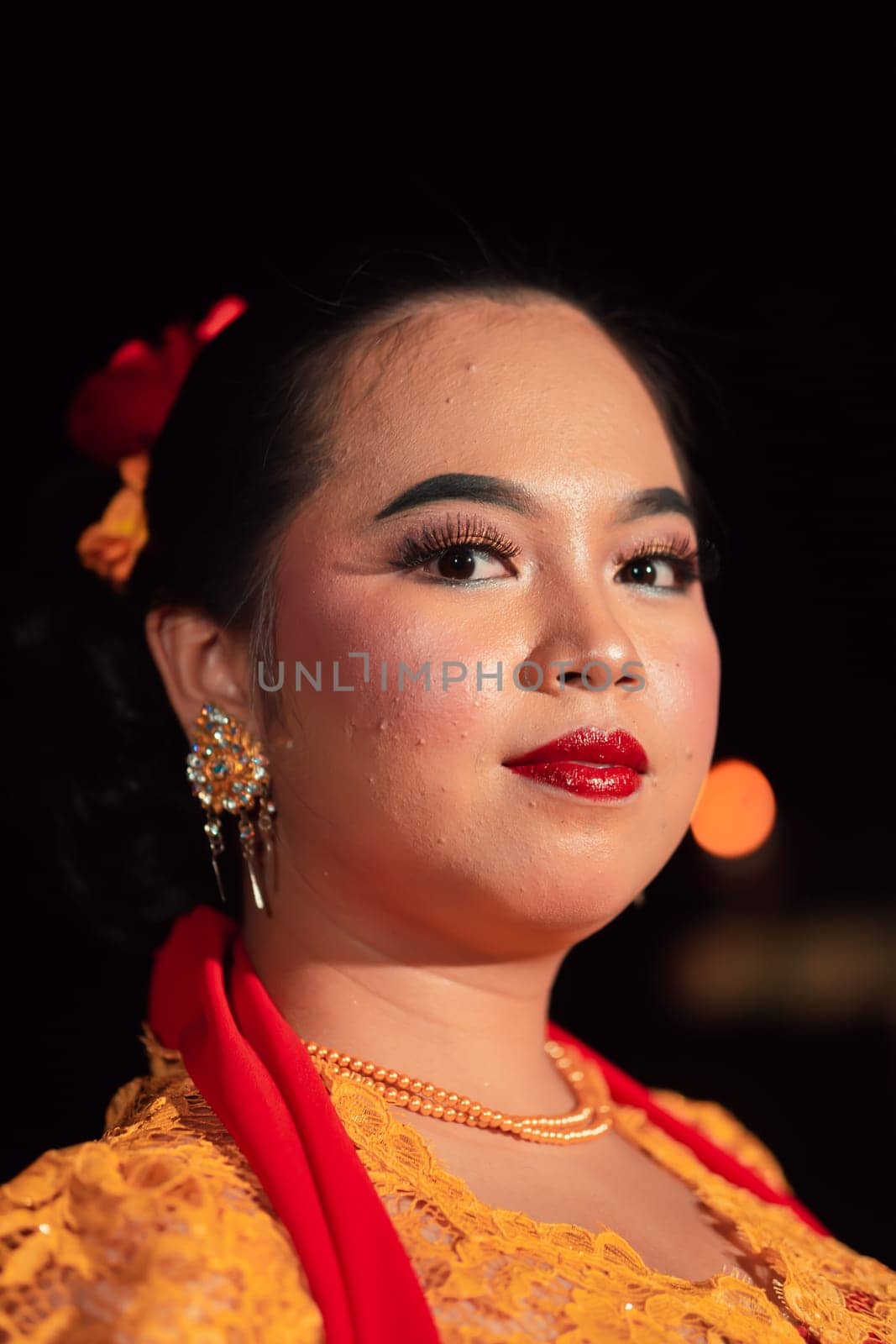 Beautiful face of an Asian woman with red lips and makeup in Indonesian traditional dance costume after the dance performance in the stage