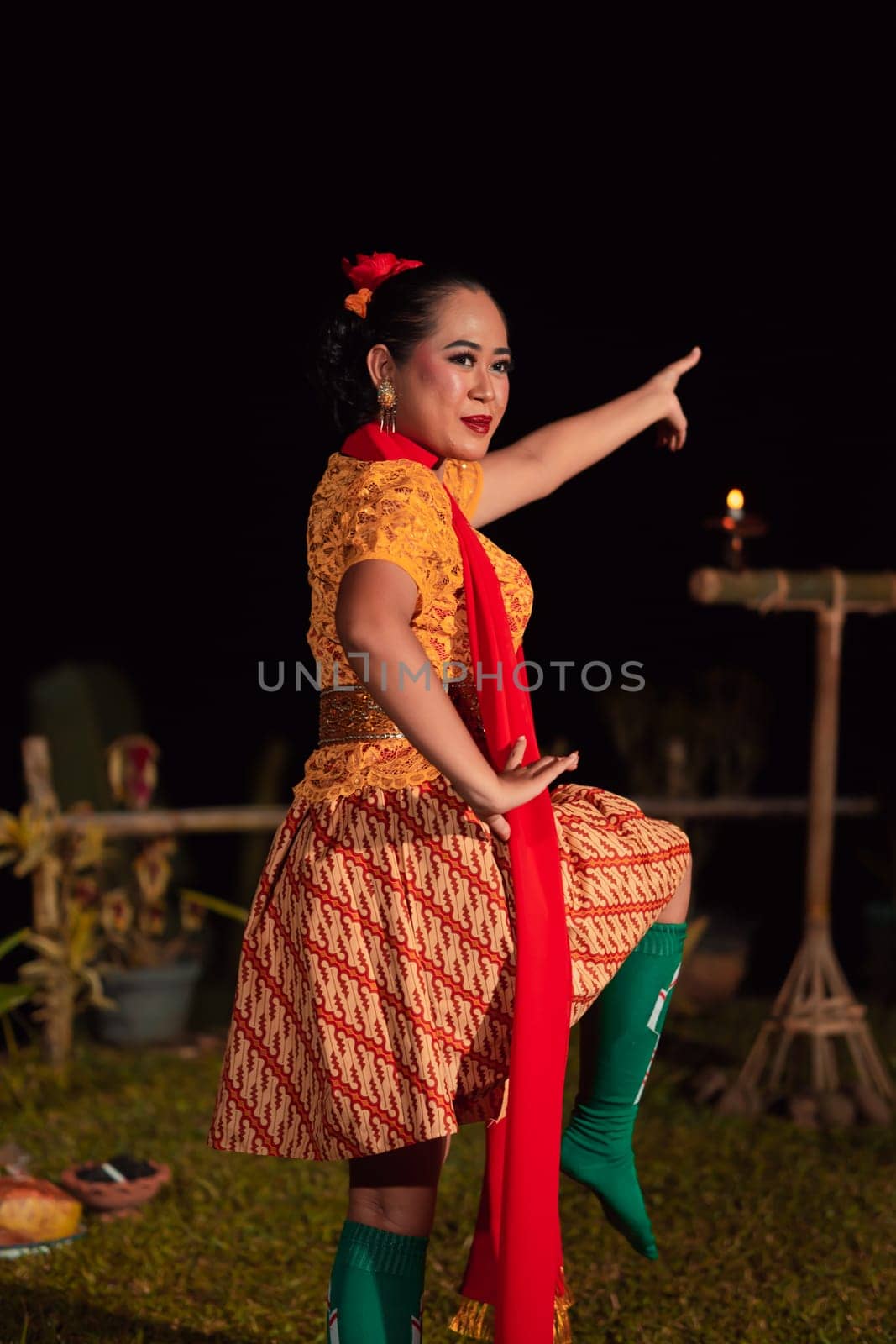 Asian woman performing a traditional dance called jaipong in Indonesia with a yellow dress and red scarf at the dance festival