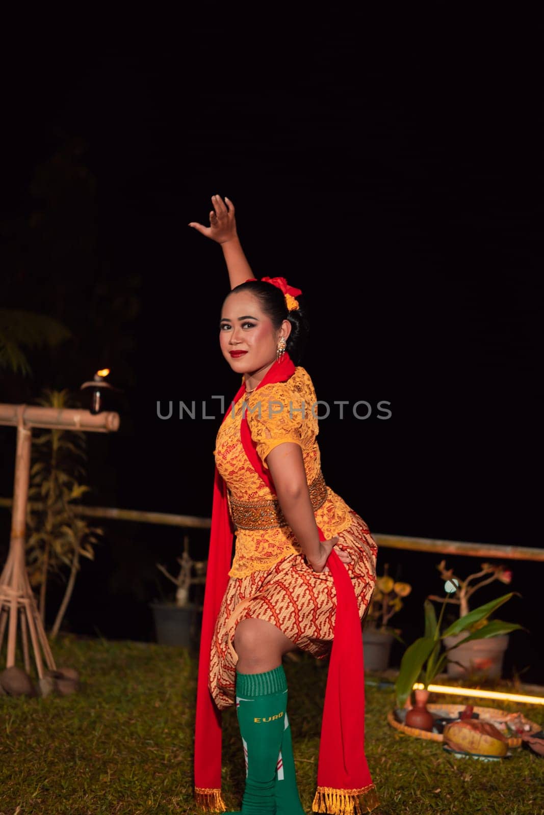 Asian woman performing a traditional dance called jaipong in Indonesia with a yellow dress and red scarf at the dance festival