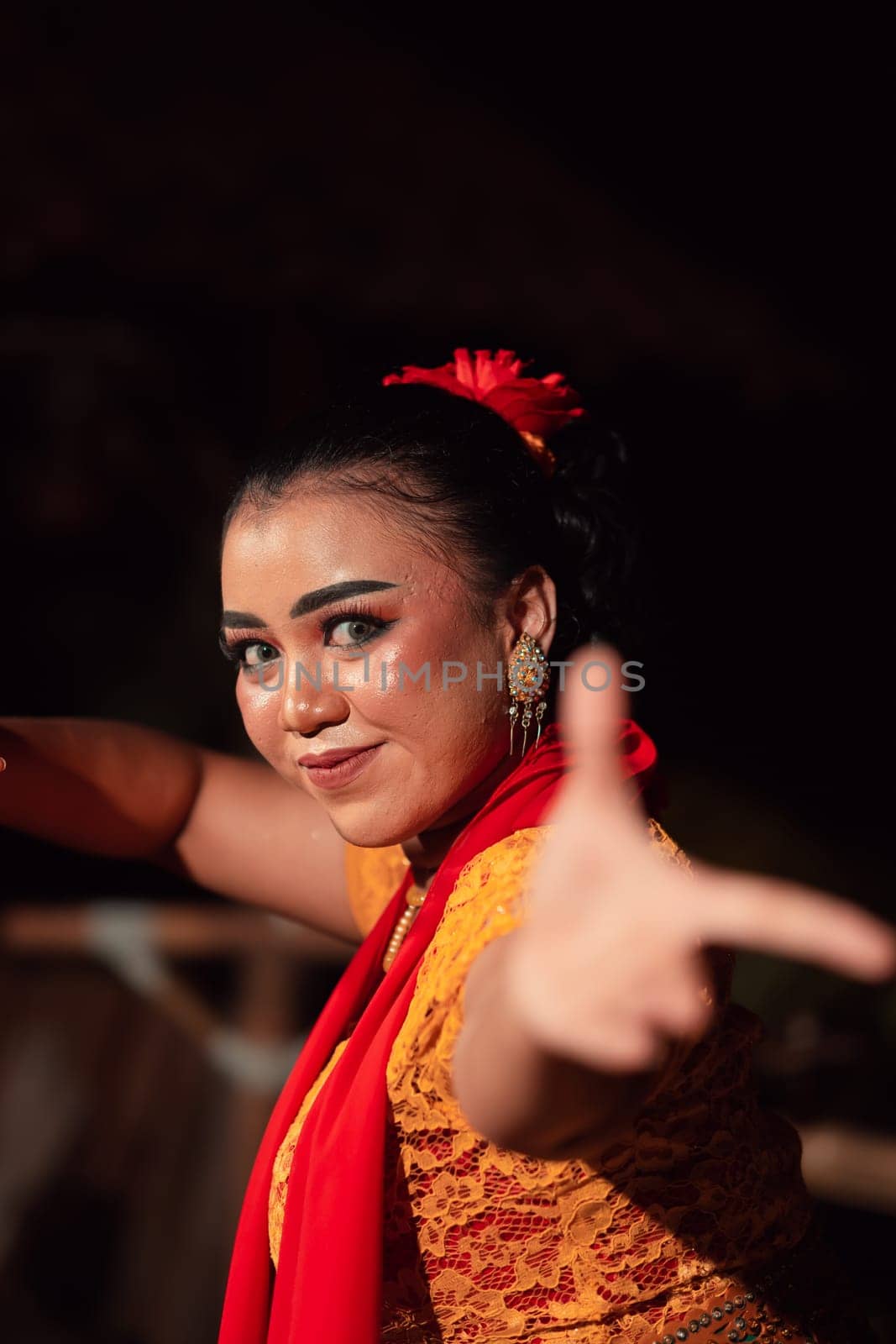 Beautiful face of an Indonesian woman in makeup while dancing a traditional dance in an orange costume during the festival in the night