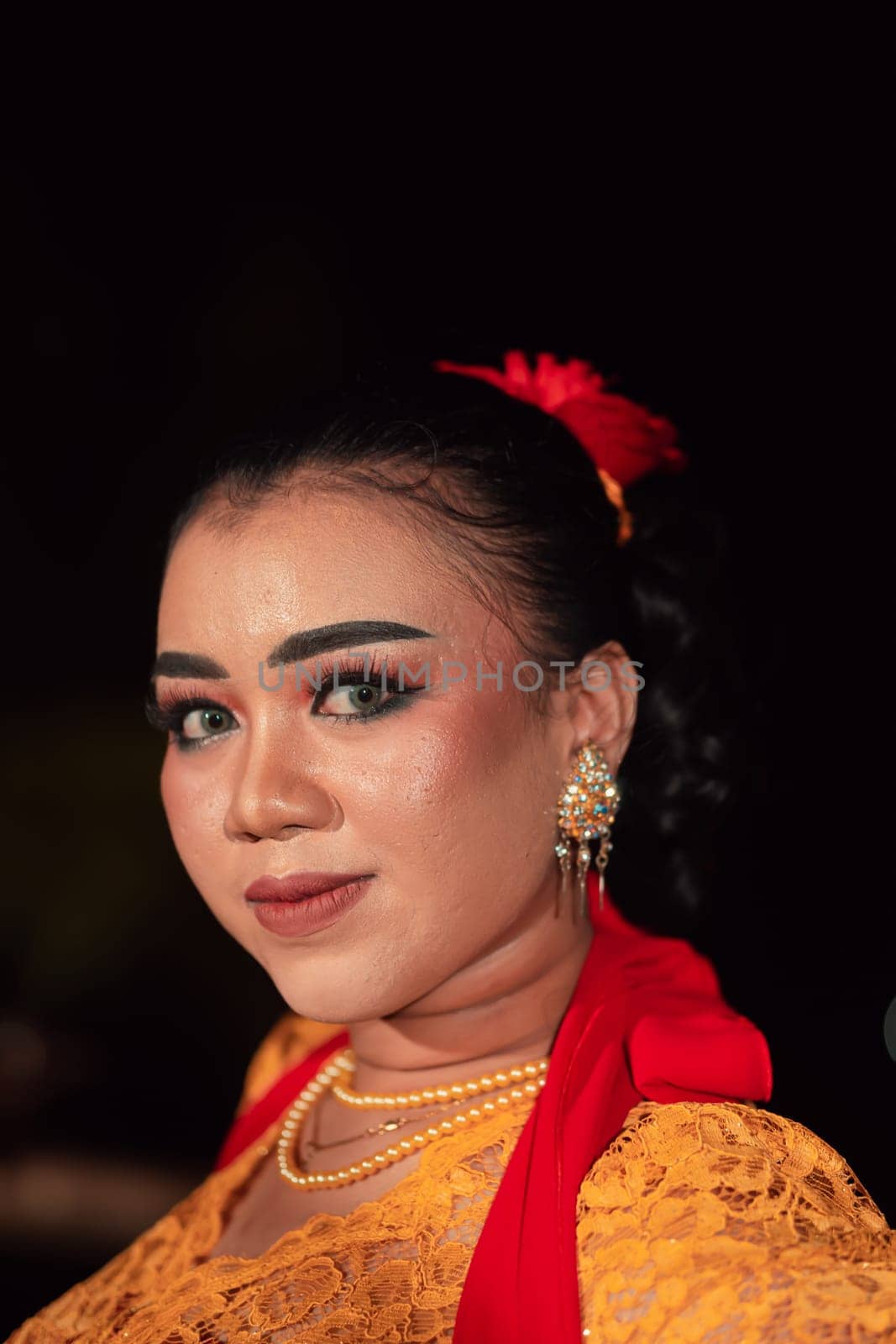 Sharp eyes from Indonesian women with makeup while wearing an orange dress at the dancing festival in the night
