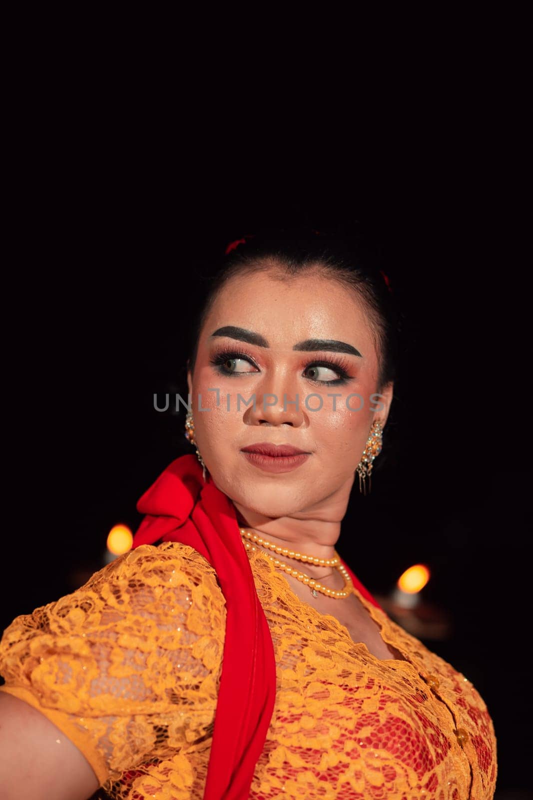 Javanese woman in a traditional orange dress while wearing makeup and a red scarf at a dance festival in Indonesia