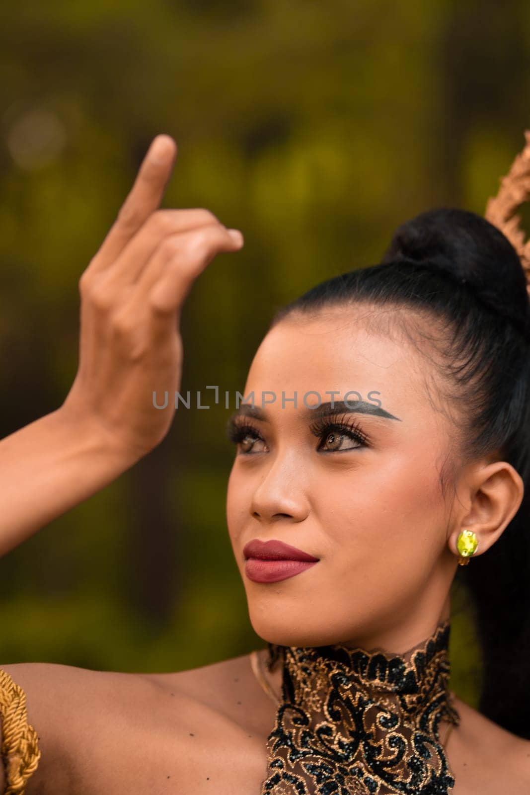 Portrait of a Balinese woman with beautiful makeup and tied black hair on a brave facial expression inside the jungle