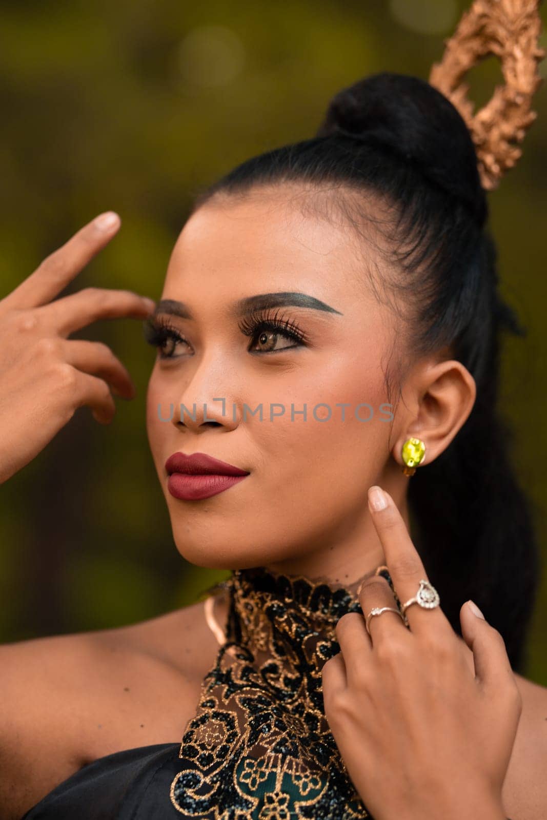 Beautiful Asian woman with makeup and tied black hair wearing a piece of black jewelry before performing dancing on the stage inside the jungle festival