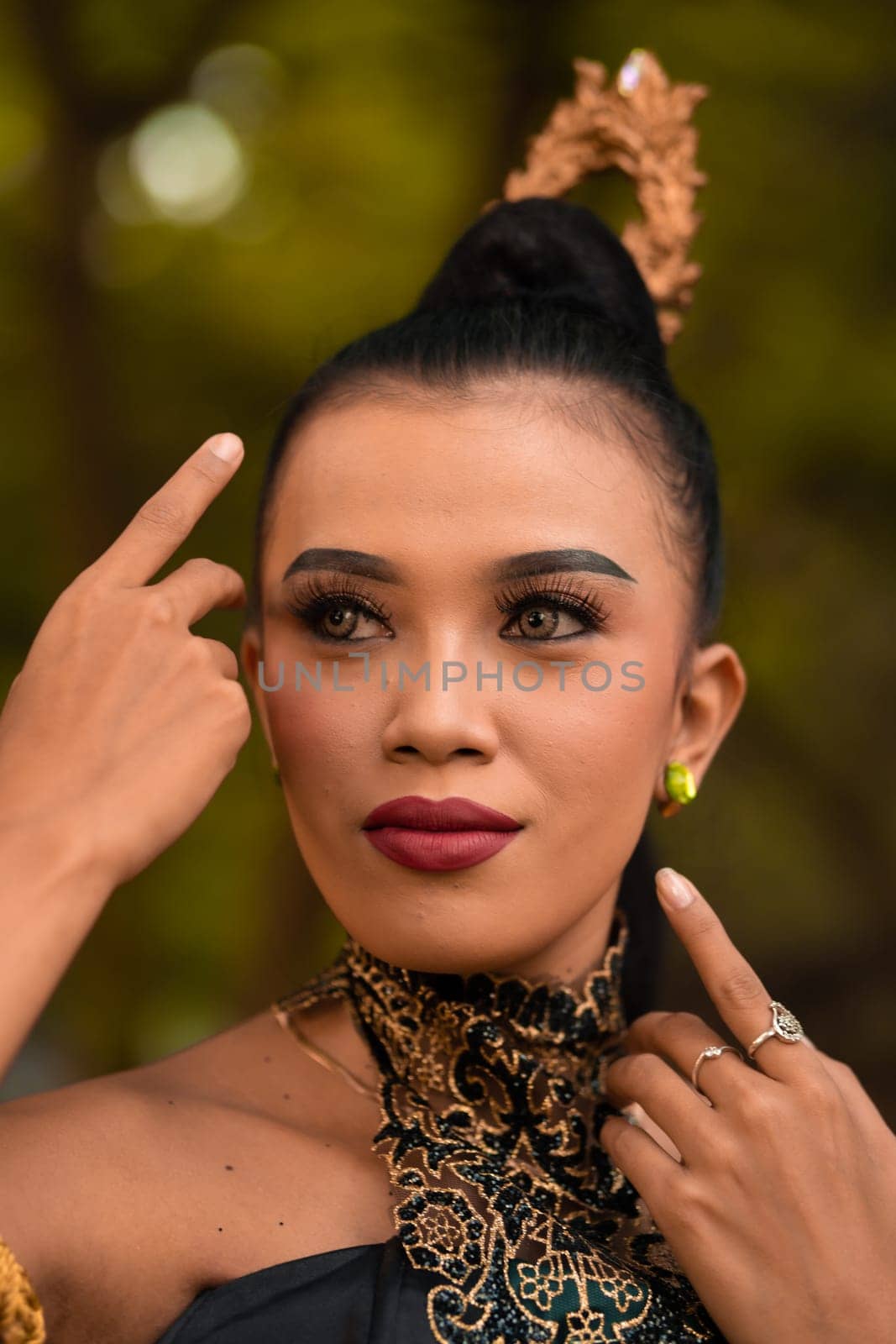 Beautiful Asian woman with makeup and tied black hair wearing a piece of black jewelry before performing dancing on the stage inside the jungle festival
