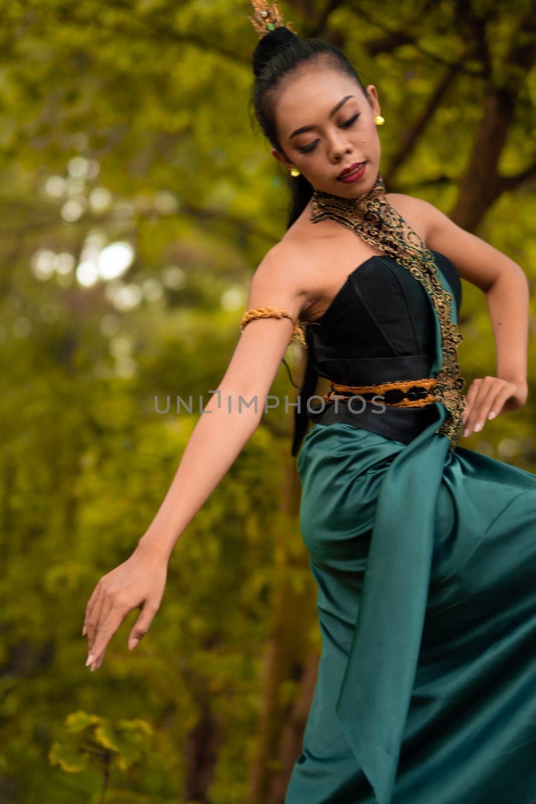 Indonesian woman dancing in the forest while wearing a traditional green costume during the festival inside the village