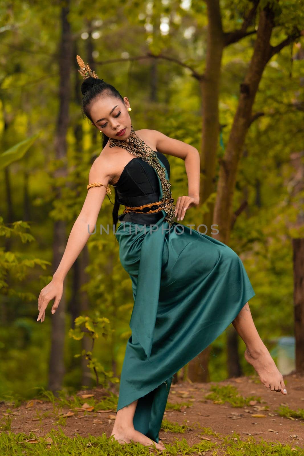 Indonesian woman dancing in the forest while wearing a traditional green costume during the festival inside the village