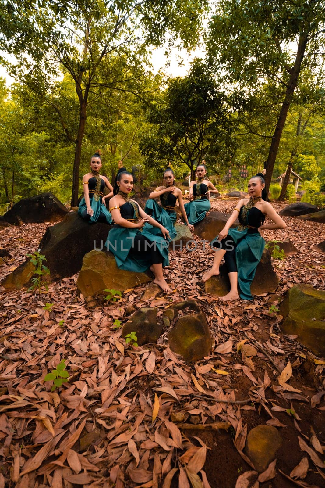 A Group of Asian women takes a vacation to the forest while wearing a green skirt and sitting on a rock during the morning
