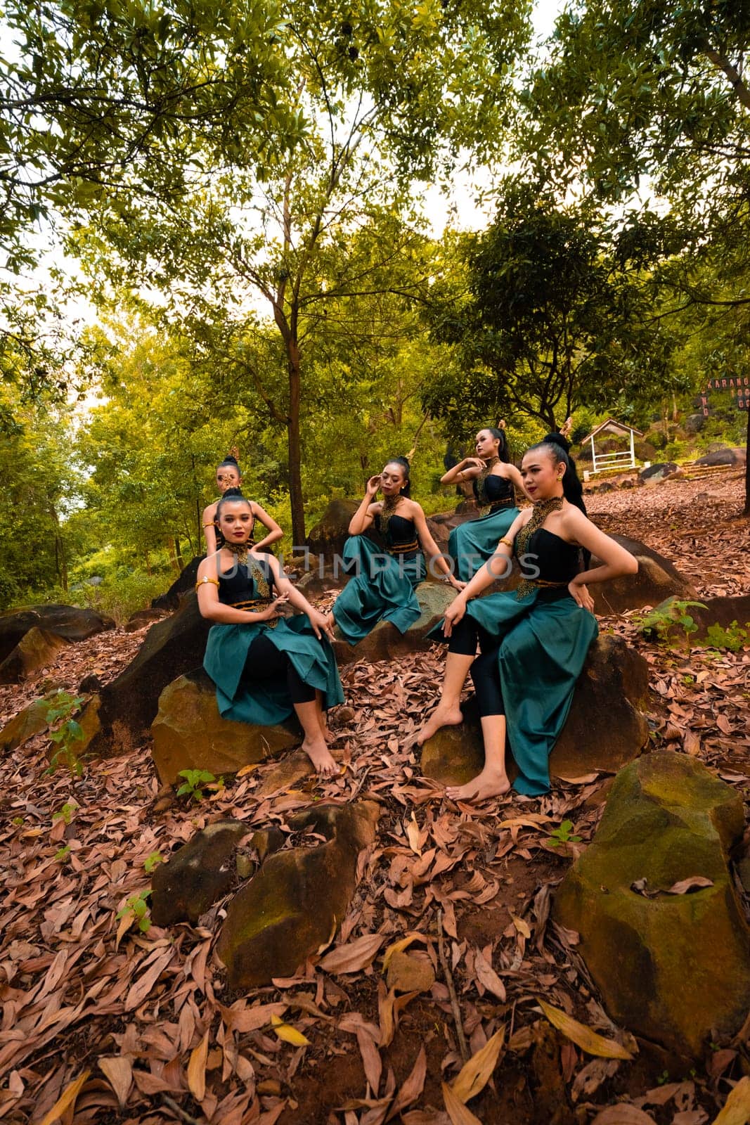 A Group of Asian women takes a vacation to the forest while wearing a green skirt and sitting on a rock during the morning