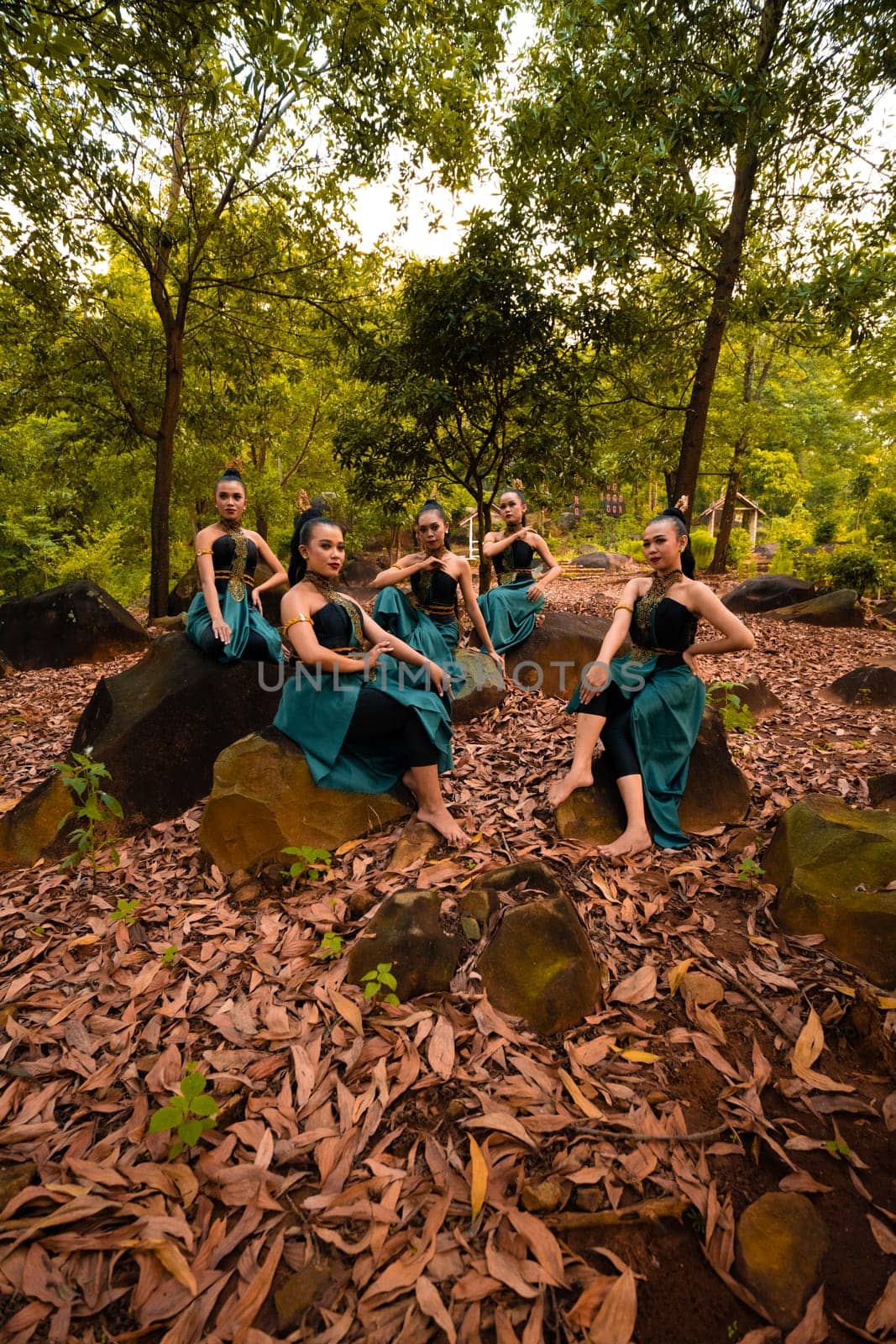 A Group of Asian women takes a vacation to the forest while wearing a green skirt and sitting on a rock during the morning