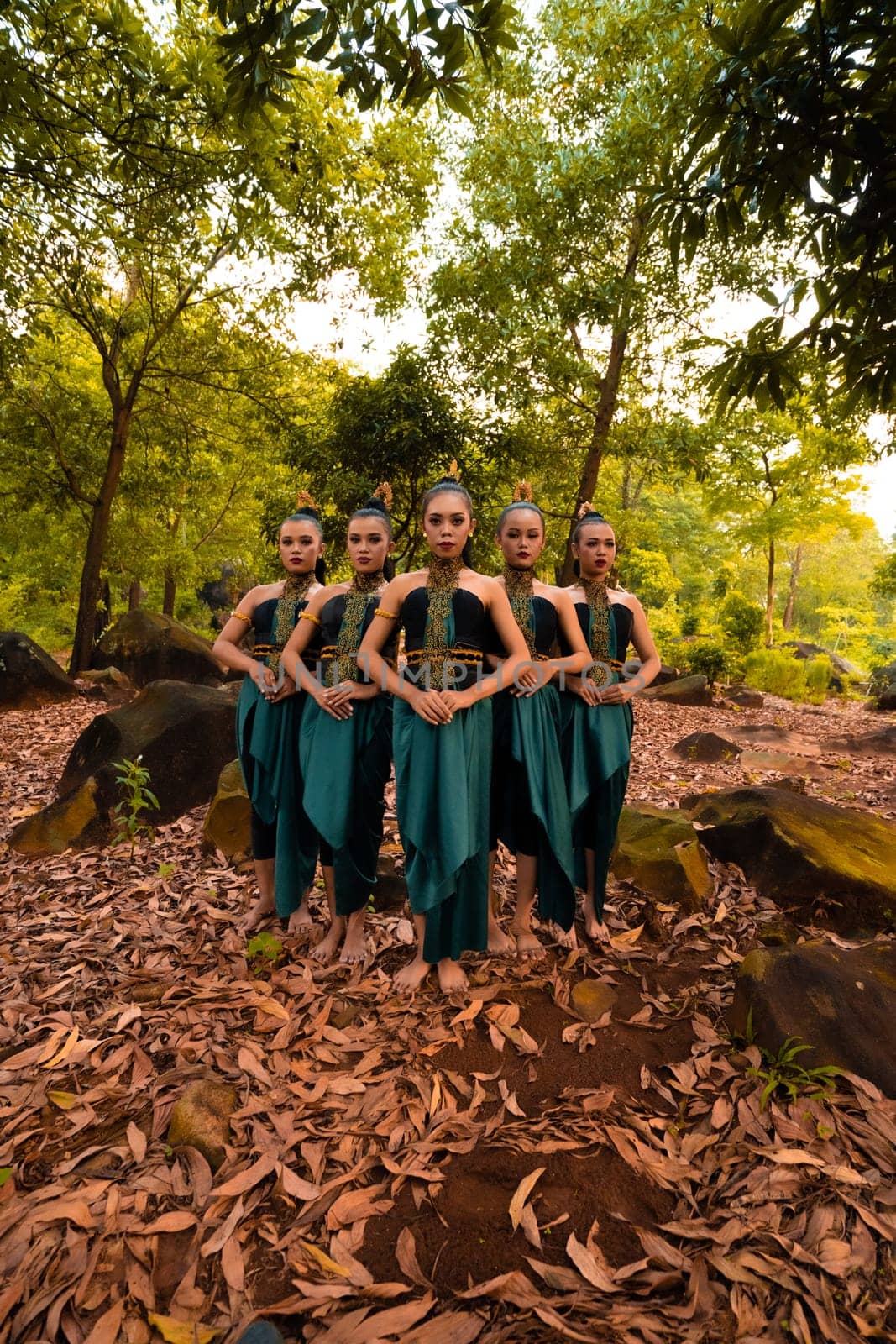 A Beautiful Asian woman in a green costume standing together in front of the forest with brown leaves in the background