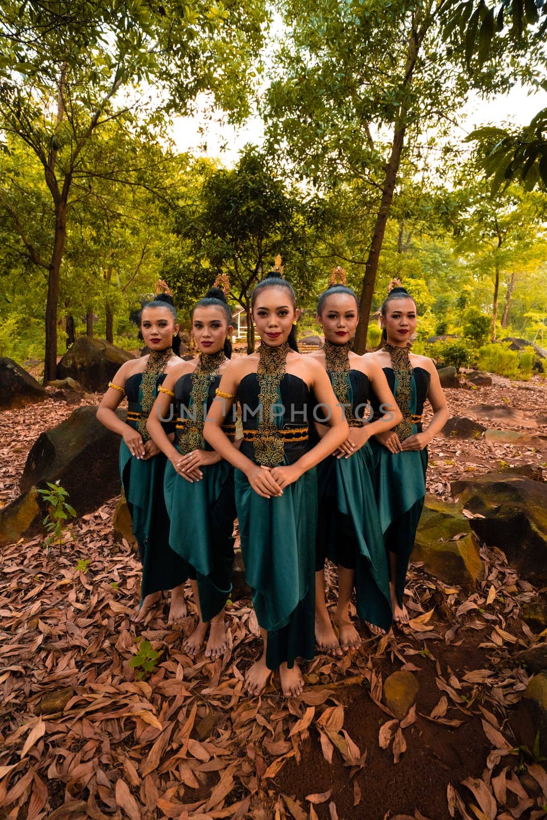 A Beautiful Asian woman in a green costume standing together in front of the forest with brown leaves in the background