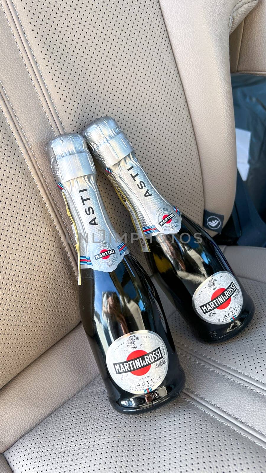 Miami, FL USA - February 05, 2025: Two bottles of MARTINI and ROSSI Asti sparkling wine placed on a luxurious beige leather car seat, showcasing elegance and sophistication during picknic.