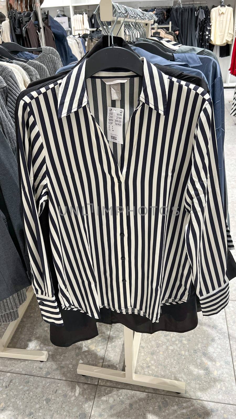Ottawa, ON Canada - February 01, 2025: A stylish striped blouse hanging on a retail display, featuring a navy and white pattern, representing fashion trends and appealing to modern women's clothing choices