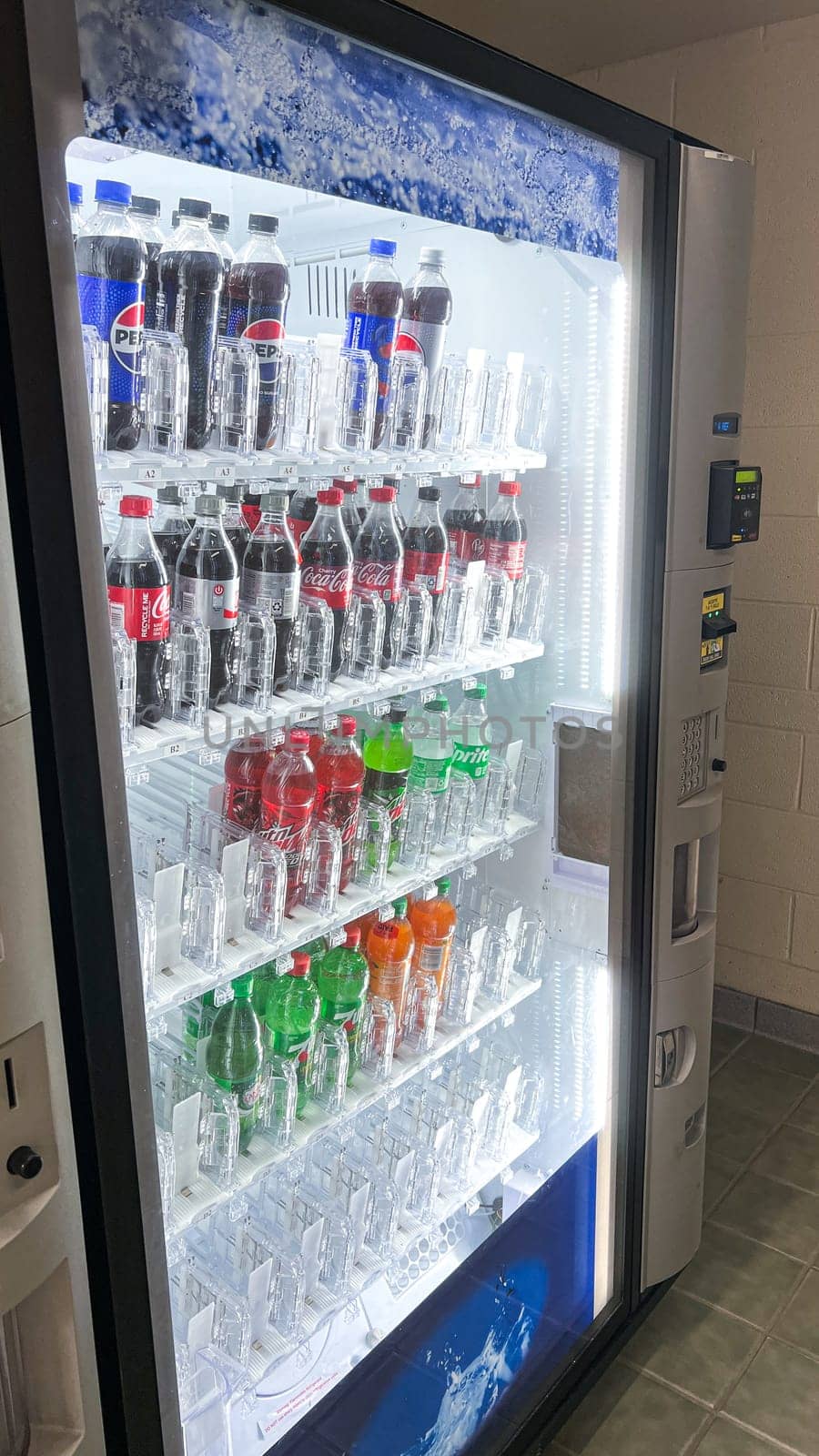 Syracuse, NY USA - March 04, 2025: Vending machine displaying an array of soft drinks like Coca-Cola and Pepsi, brightly lit to attract attention, offering a convenient selection of beverages.