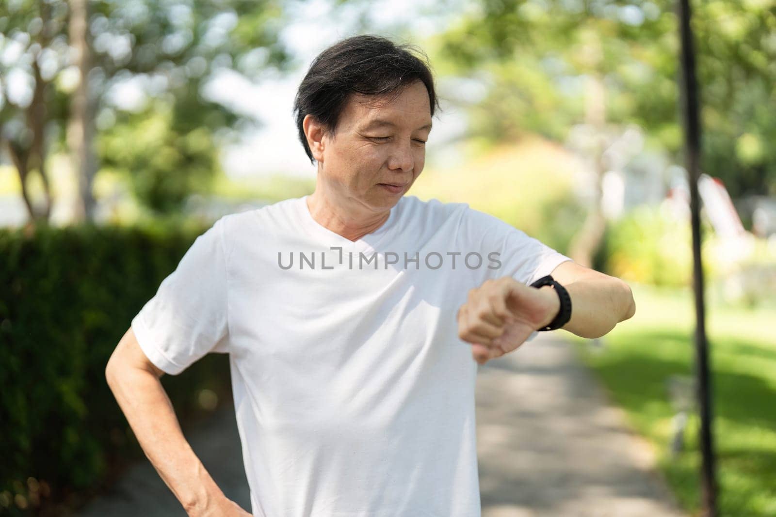 A man evaluates his fitness metrics on a smartwatch after exercising in a park, promoting a healthy lifestyle.