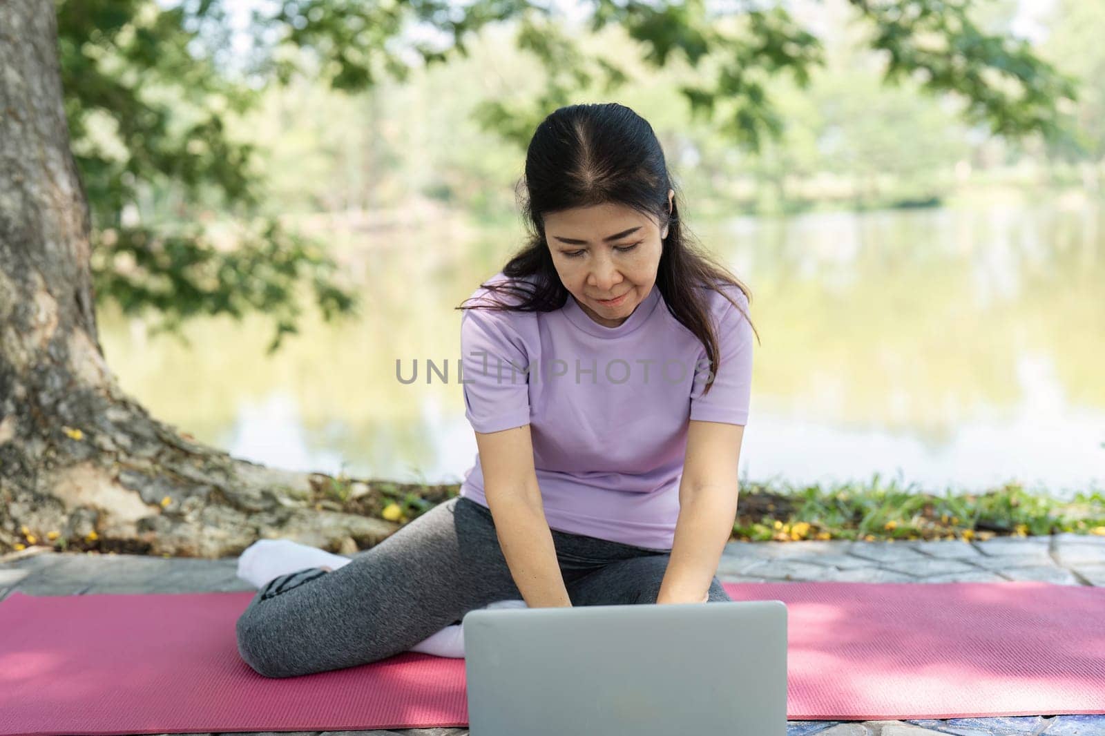 A woman engages in yoga exercises on a mat by the serene lakeside, promoting wellness and mindfulness in nature.