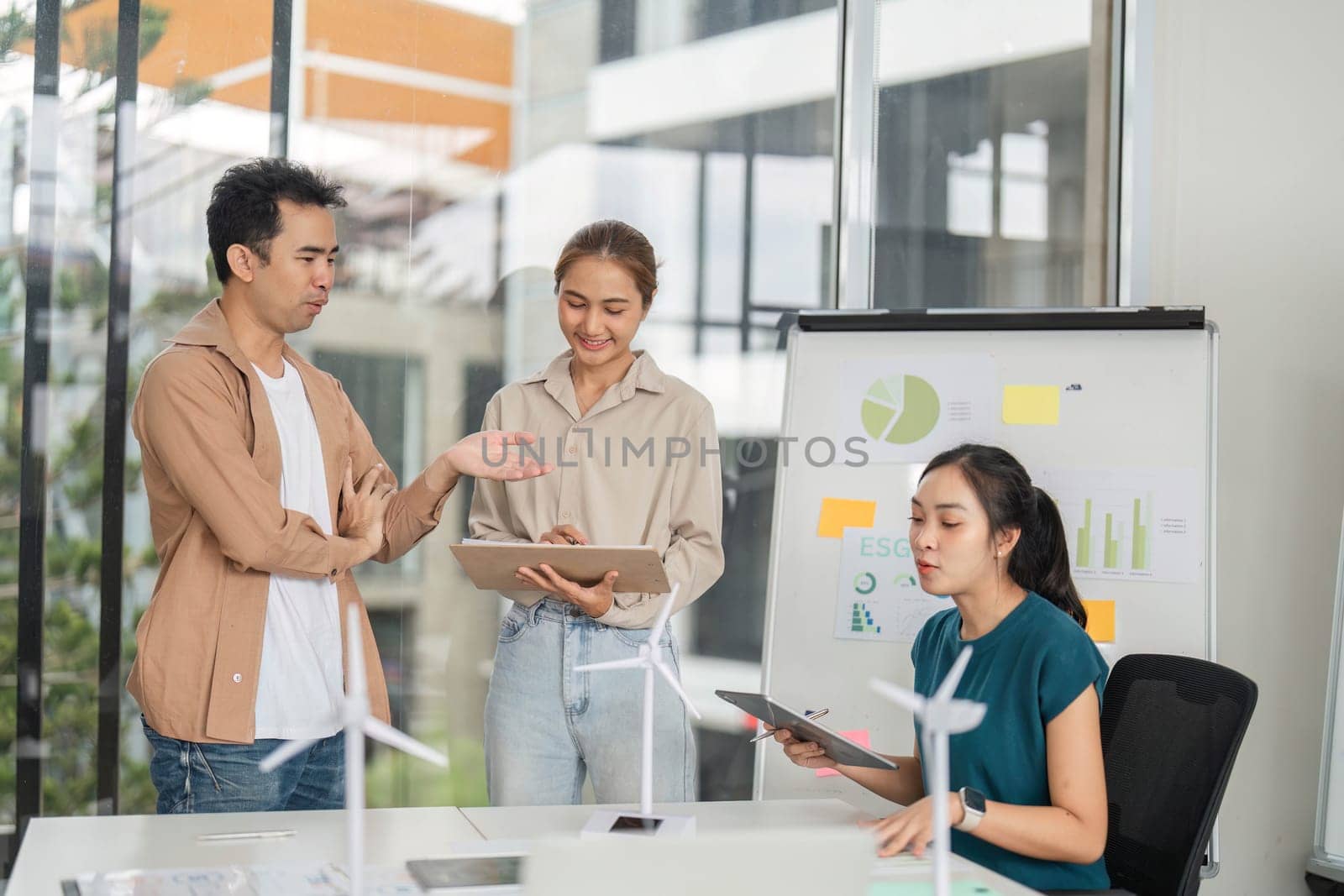 A diverse team discussing ESG strategies, showcasing graphs and data on sustainable business practices in a bright office.
