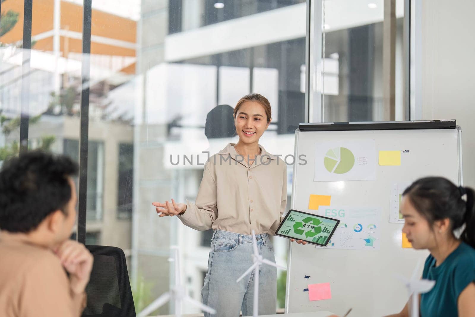 A professional woman presents ESG strategies to her team in a modern office, highlighting sustainability and business growth.