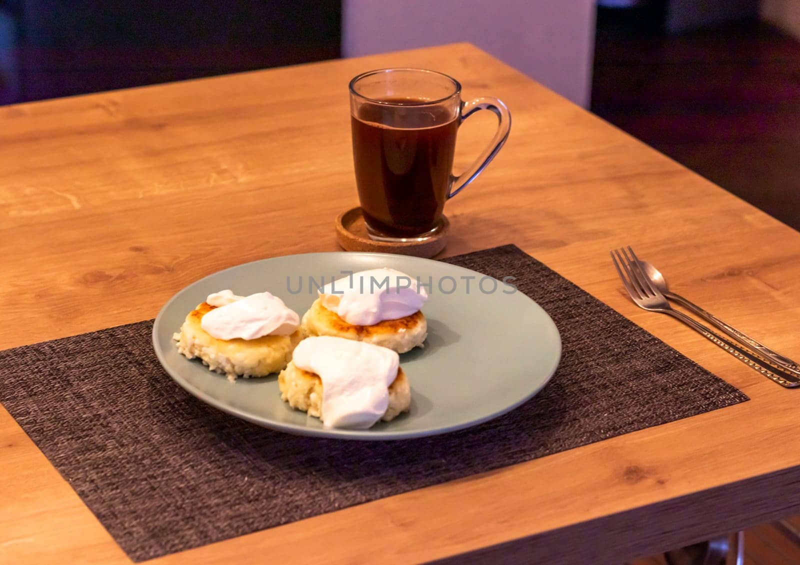 Traditional russian breakfast cheese cakes or syrniki made of cottage cheese on the plate next to cup of cofee