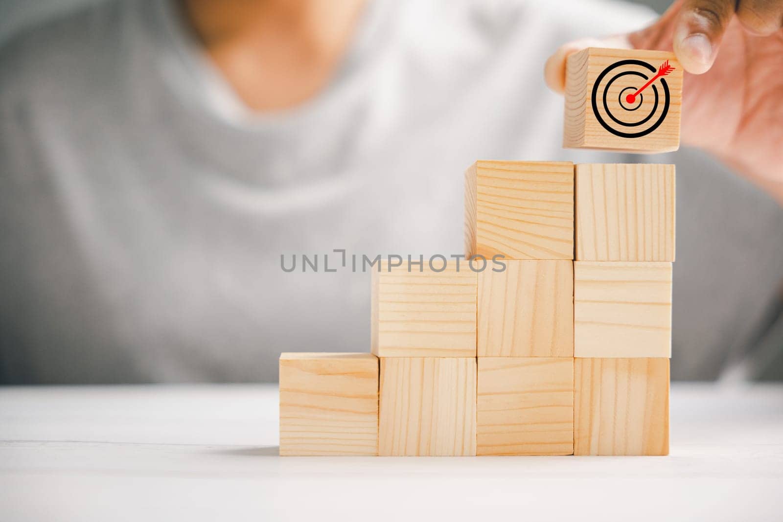 Hand arranging wood blocks to create a strategic stack, emphasizing the significance of a business strategy and action plan. Targeting business goals and success.