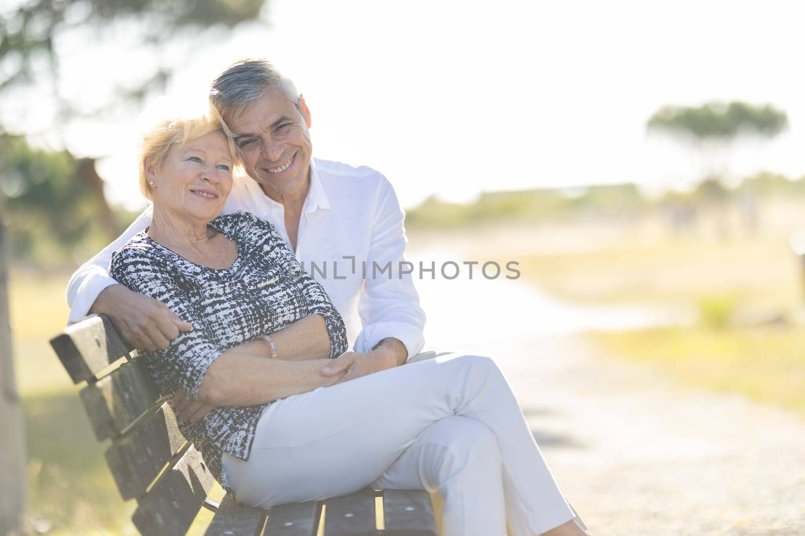 Senior couple enjoying retirement together while sitting on a park bench and embracing each other