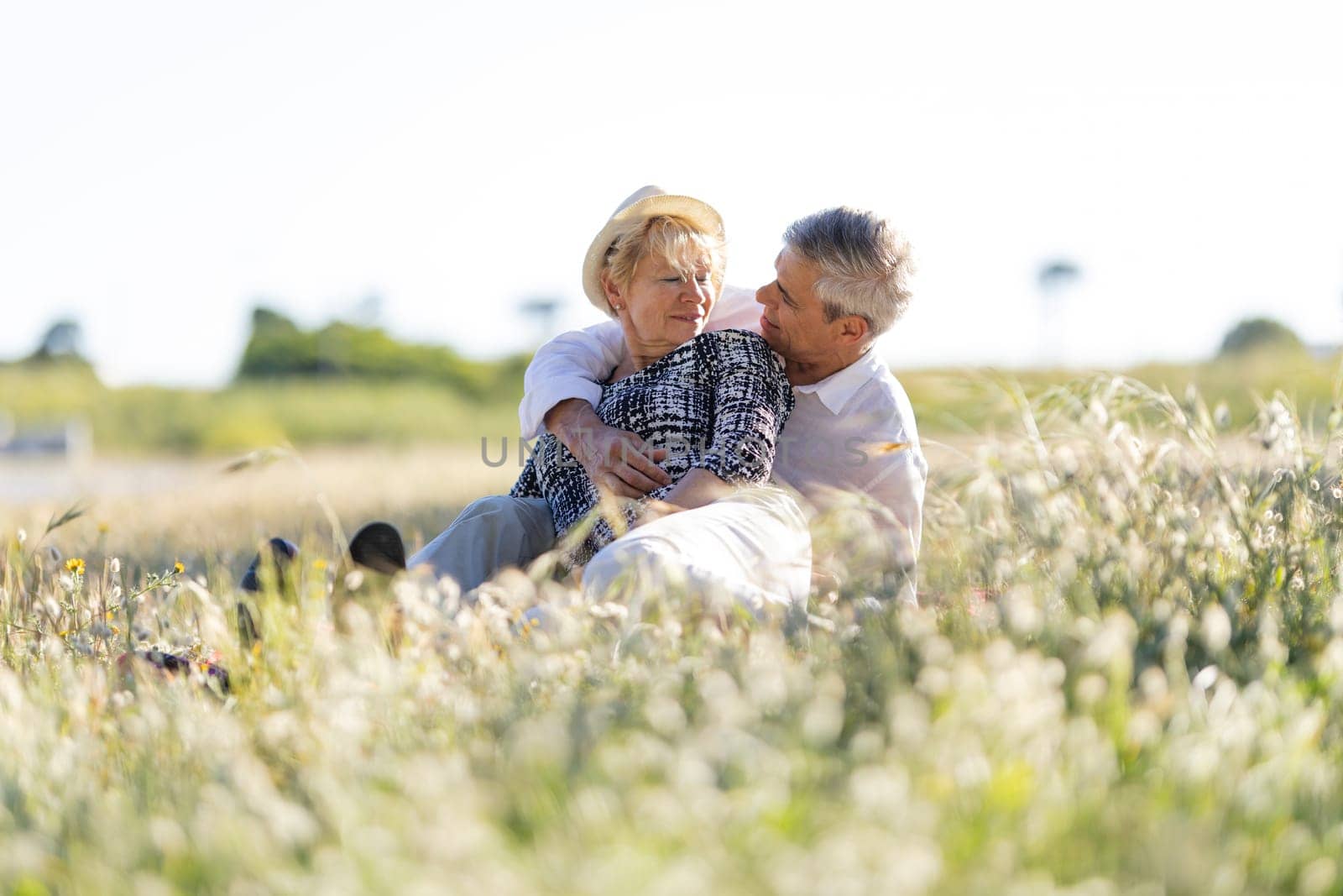 Senior couple relaxing in a meadow, embracing and enjoying retirement together
