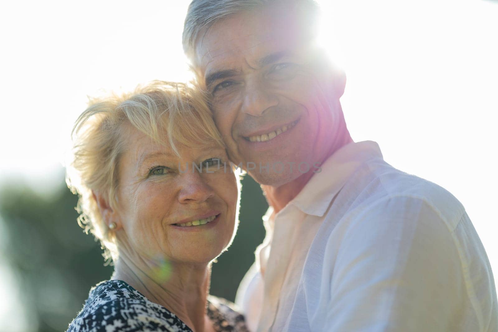Portrait of happy senior couple smiling together outdoors in bright sunlight