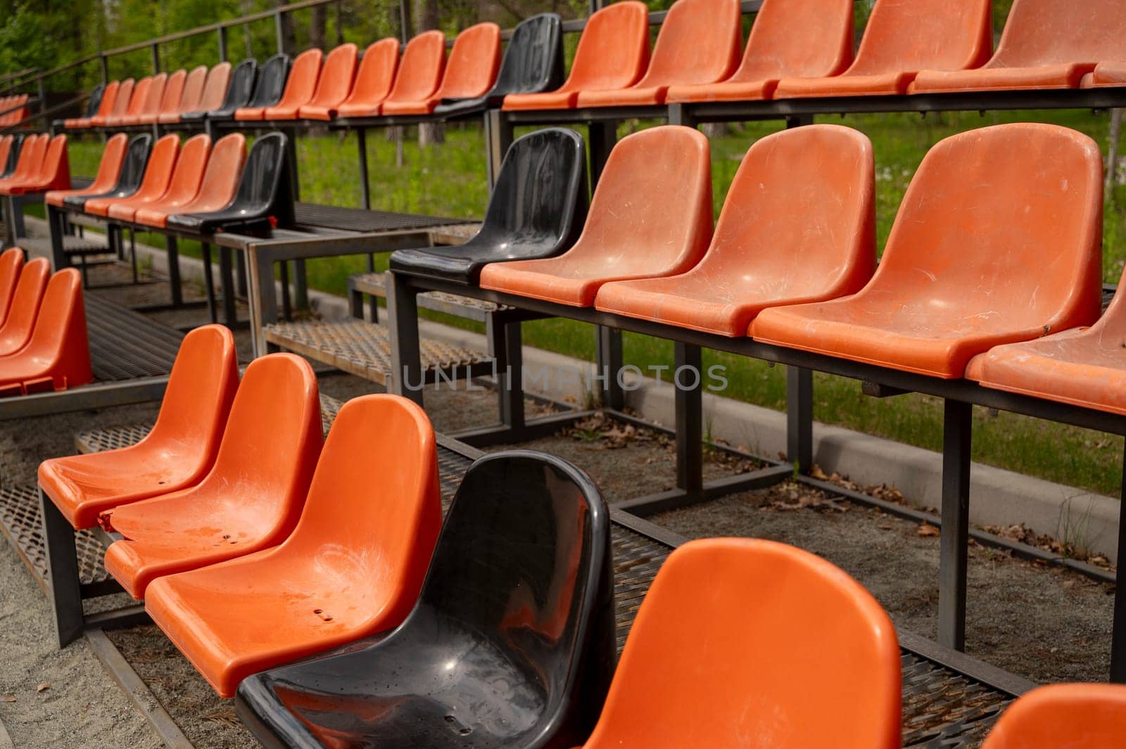 Close up of Rows of empty orange and black plastic seats on grandstand near outdoor sports stadium. High quality photo