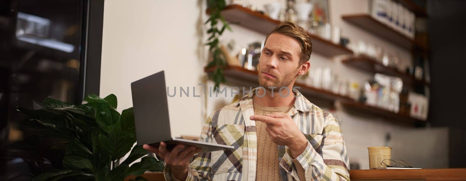 You got a point. Portrait of serious man agree with colleague, pointing finger at laptop screen, connects to video chat, has conversation with someone.