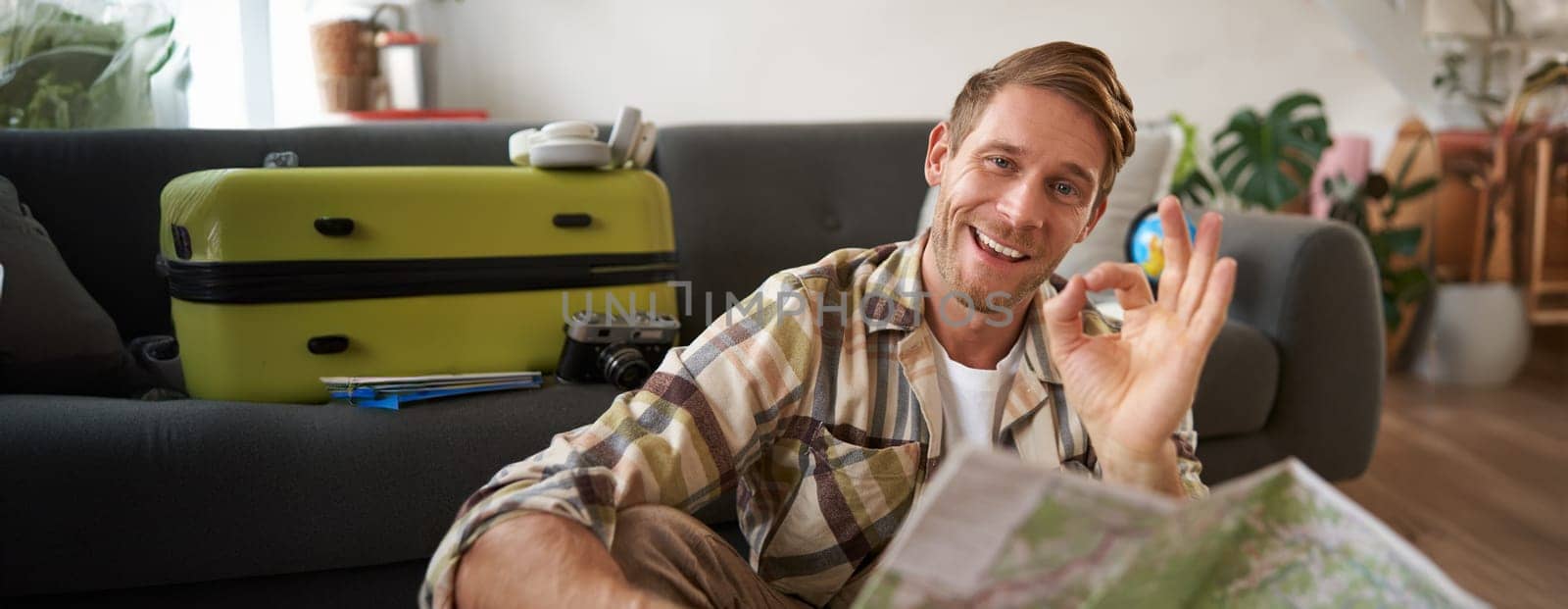 Good-looking guy, tourist with travel map, shows okay, ok sign, approve route or holiday destination, Tourism and people concept