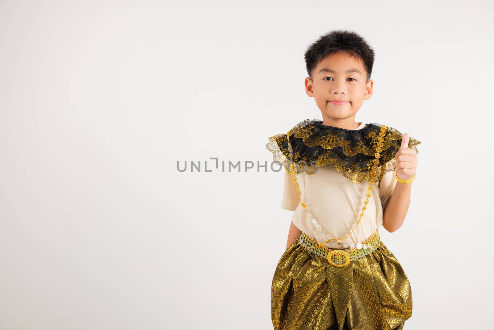 Portrait Thailand kid boy smiling traditional Thai dress costume makes thumbs up OK sign, symbolizing agreement, studio isolated white background, primary child radiates positivity and satisfaction