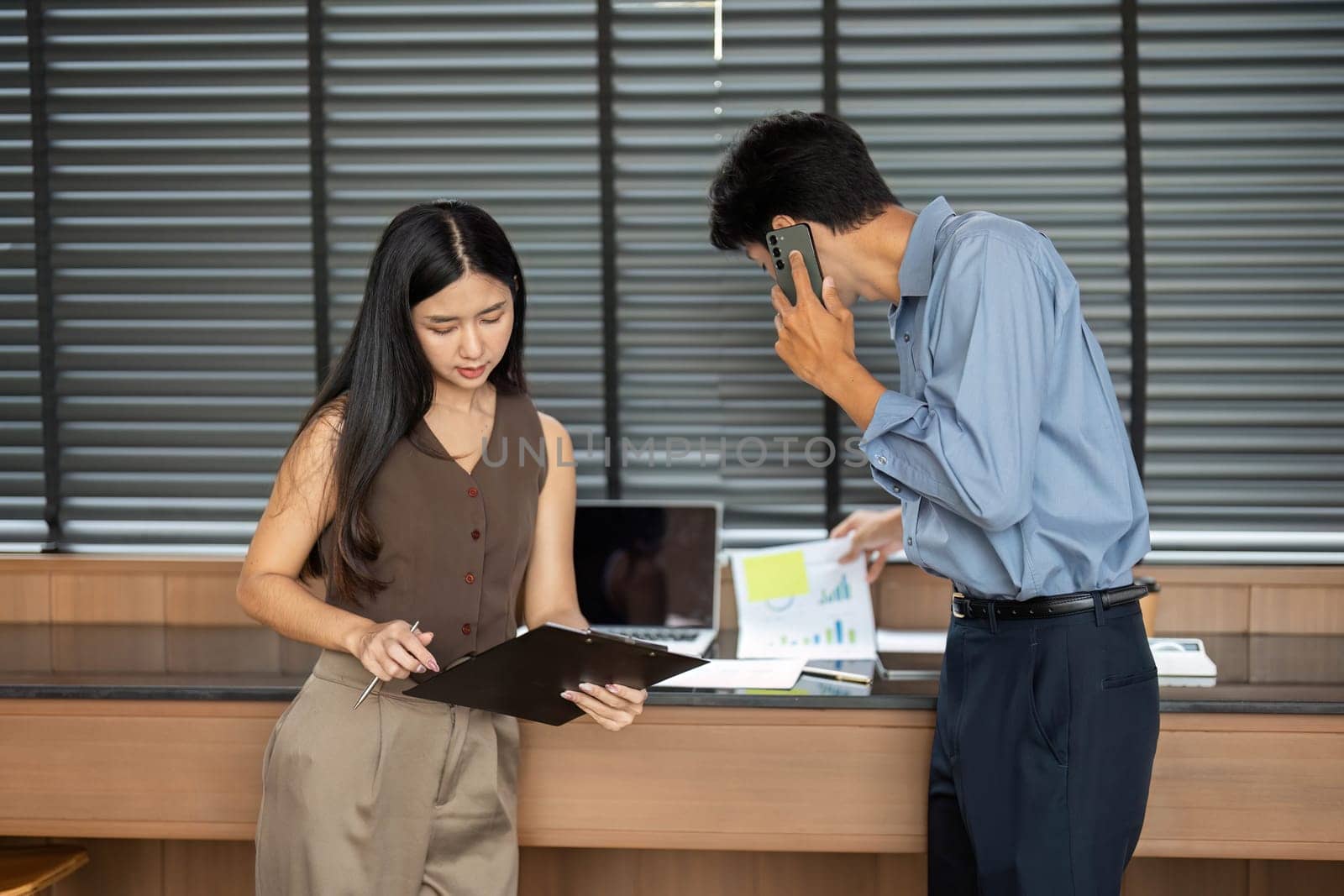 A businesswoman and businessman engaged in an interactive session, reviewing data and documents in a stylish office environment.
