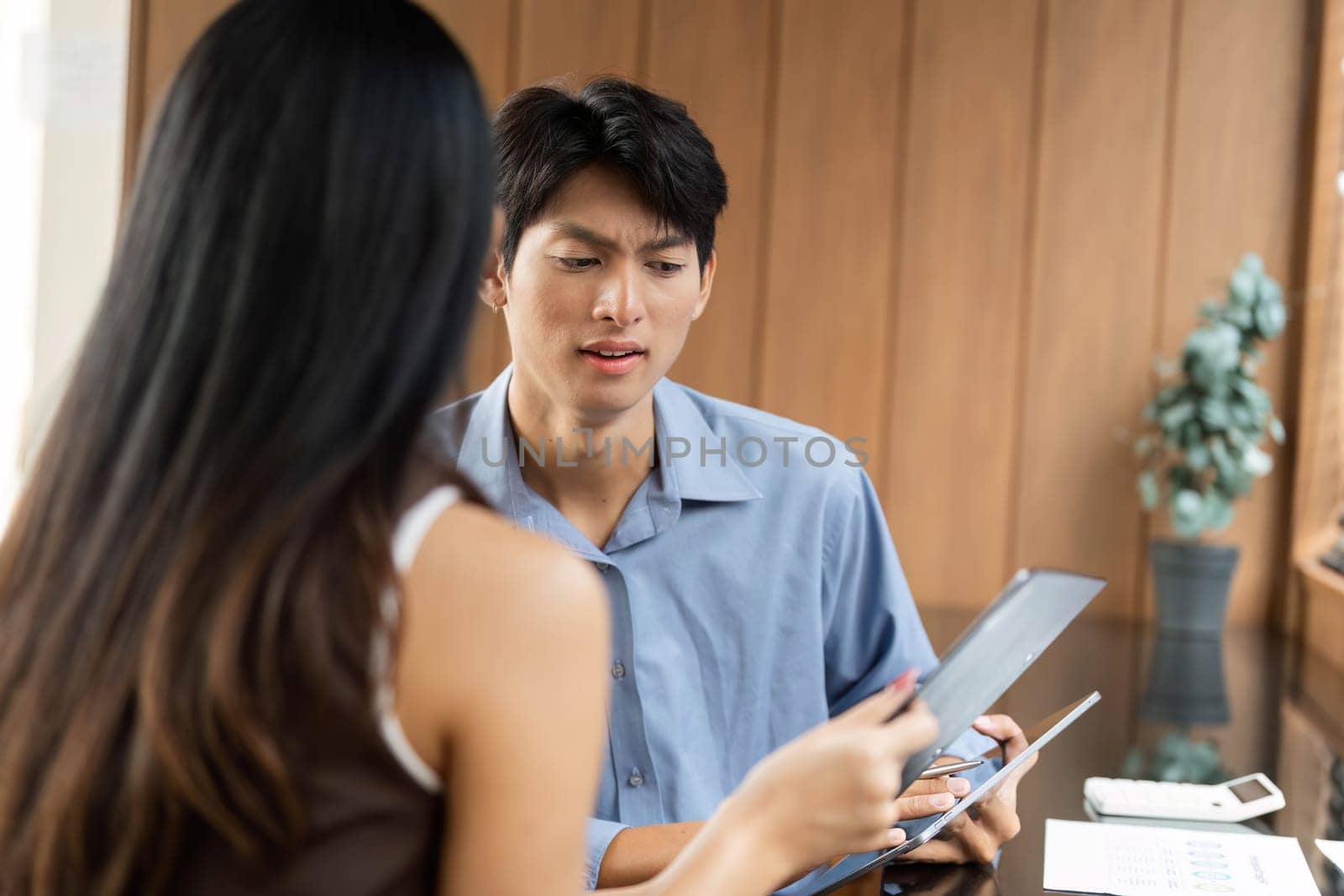 Two colleagues engaged in a serious conversation about financial strategies, reviewing data in a contemporary workspace.