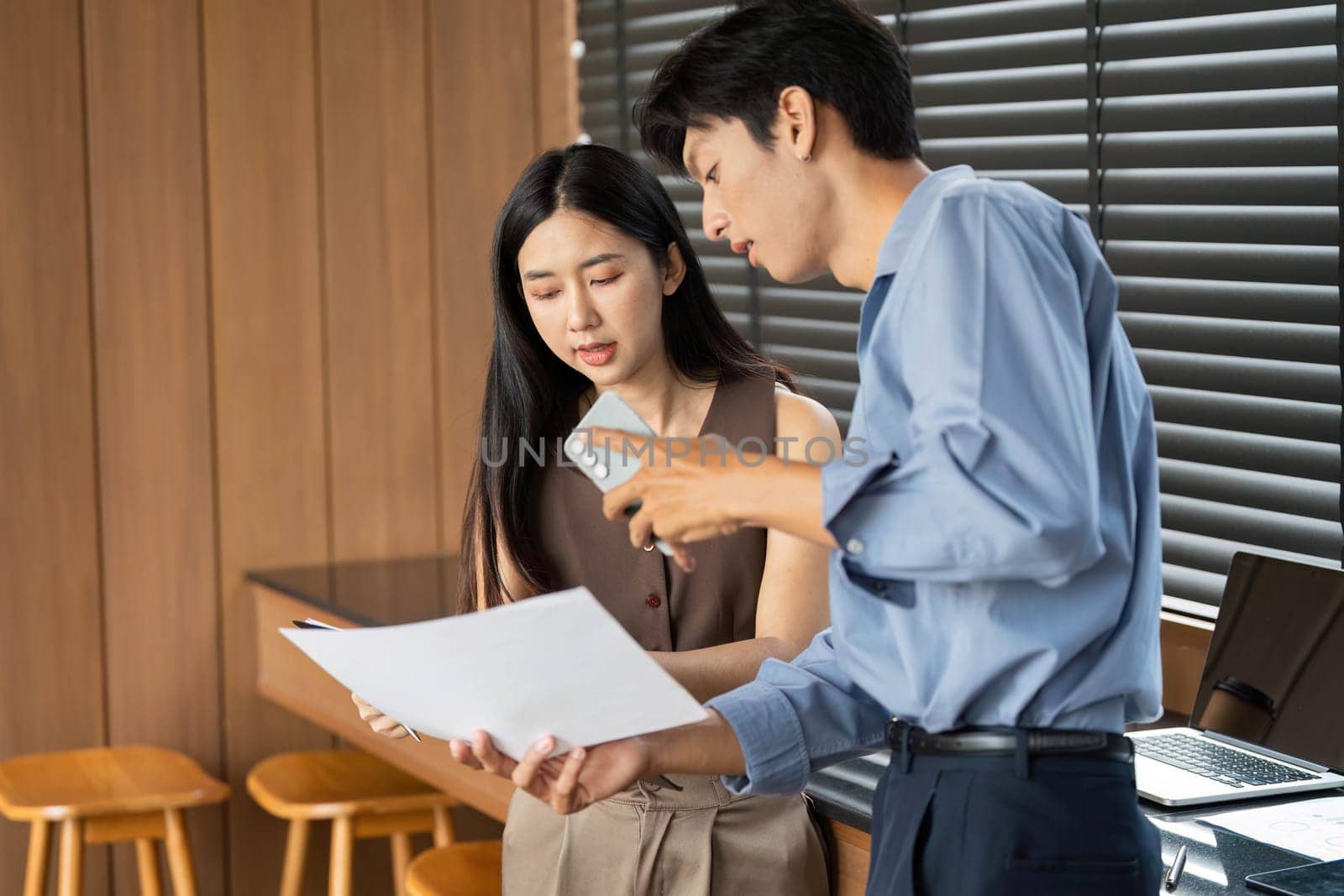 A businesswoman and businessman review project documents together, focusing on collaboration and strategy in a contemporary workspace.
