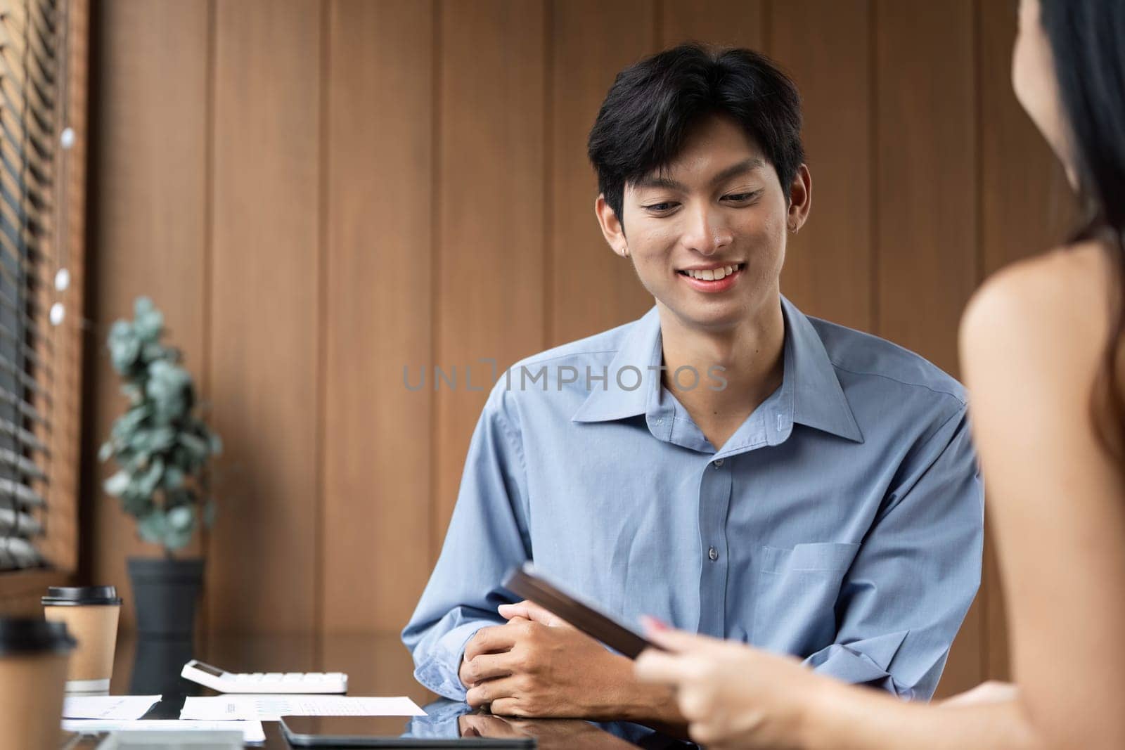 Two colleagues engage in a business discussion, analyzing financial data on digital tablets in a contemporary workspace.