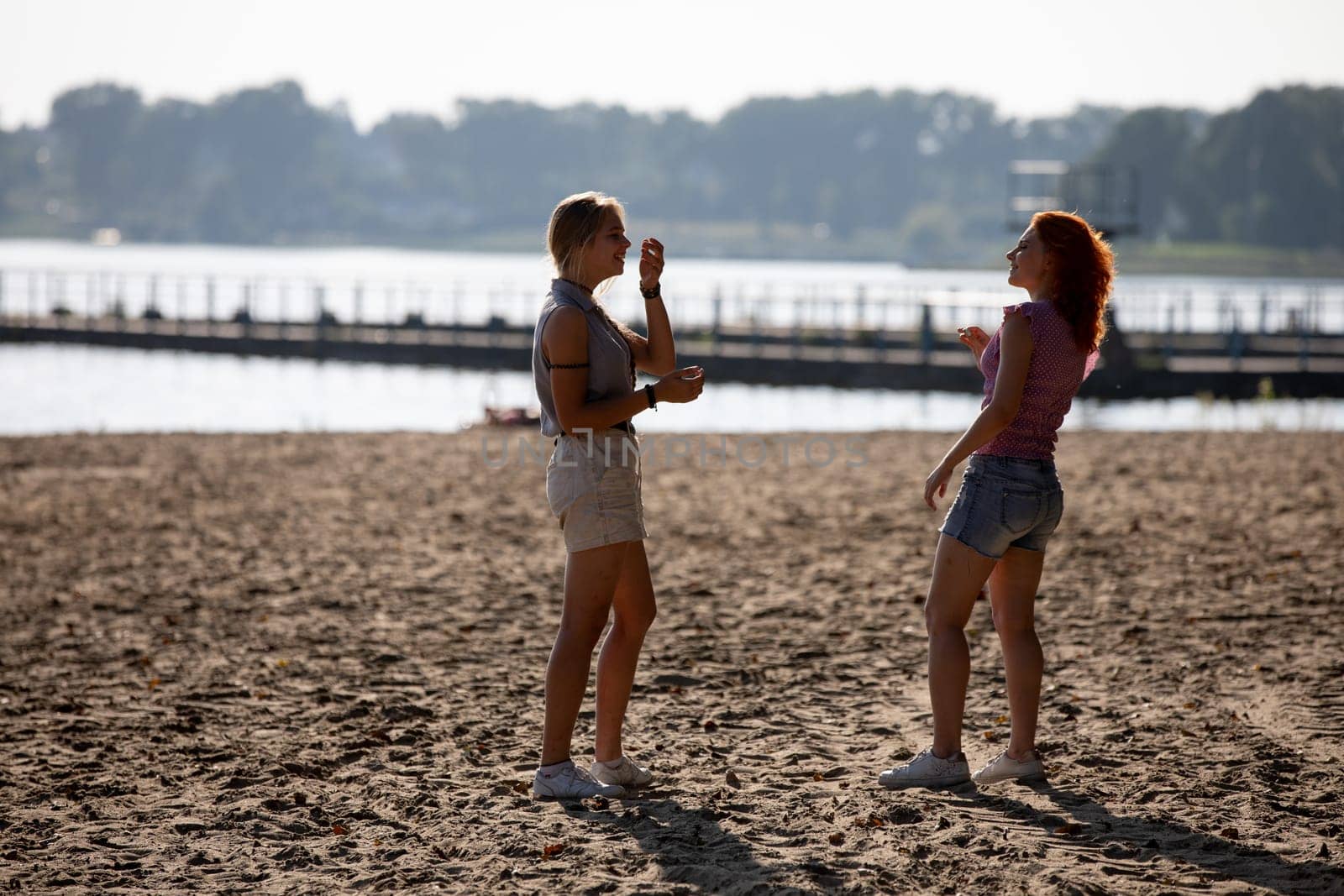 Two close friends share laughter and delight in ice cream on a beautiful, sunny beach, capturing joyful summer moments