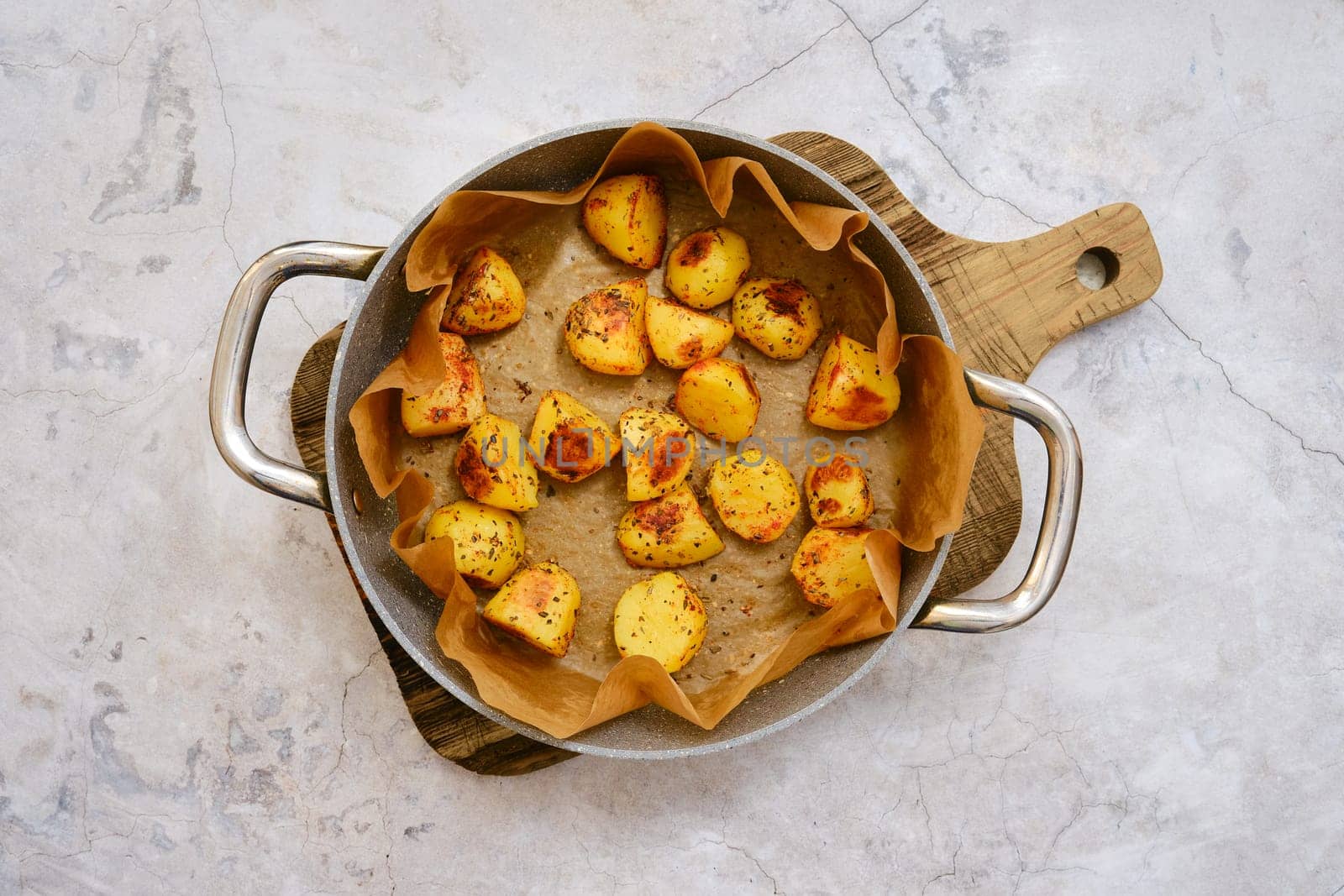 Golden brown roasted potatoes are beautifully arranged in a serving platter lined with parchment paper.