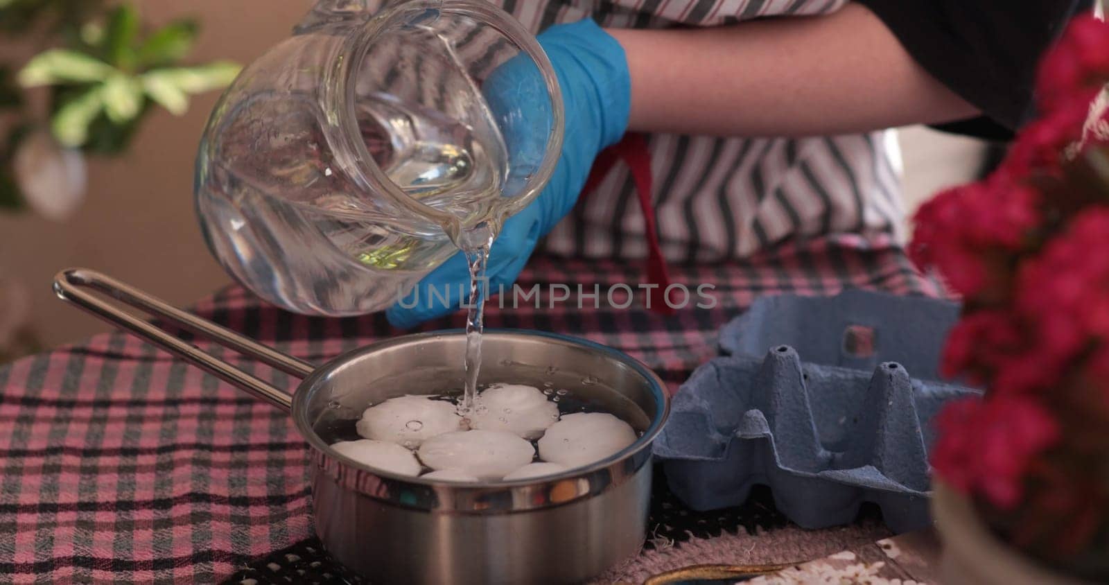 Water is being poured into a pot containing eggs, getting ready for boiling. This activity is part of the process of making colorful Easter eggs for decoration and celebration.