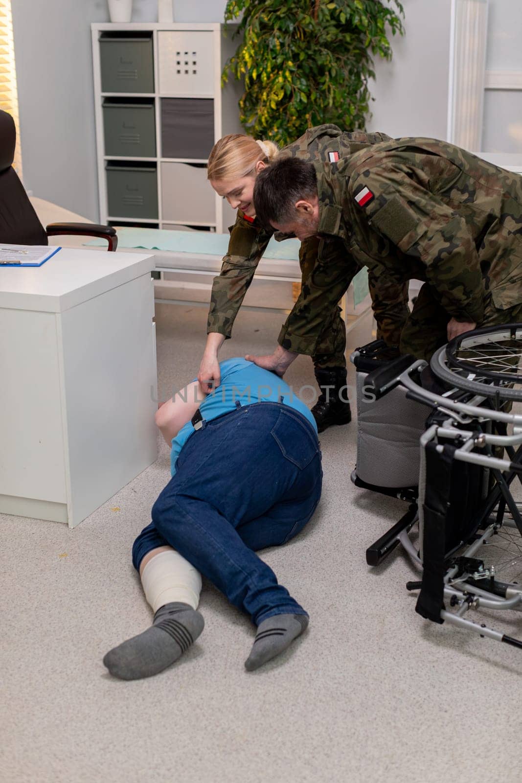 A detailed scene depicting military personnel actively assisting an injured person in a realistic training scenario