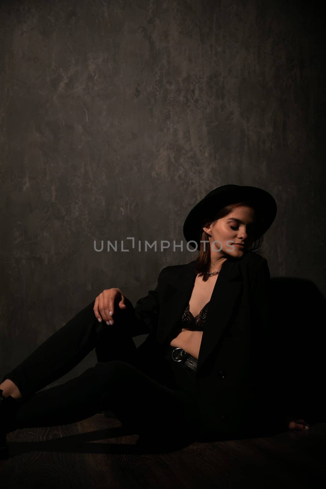 Beautiful woman in black jacket and hat on dark background