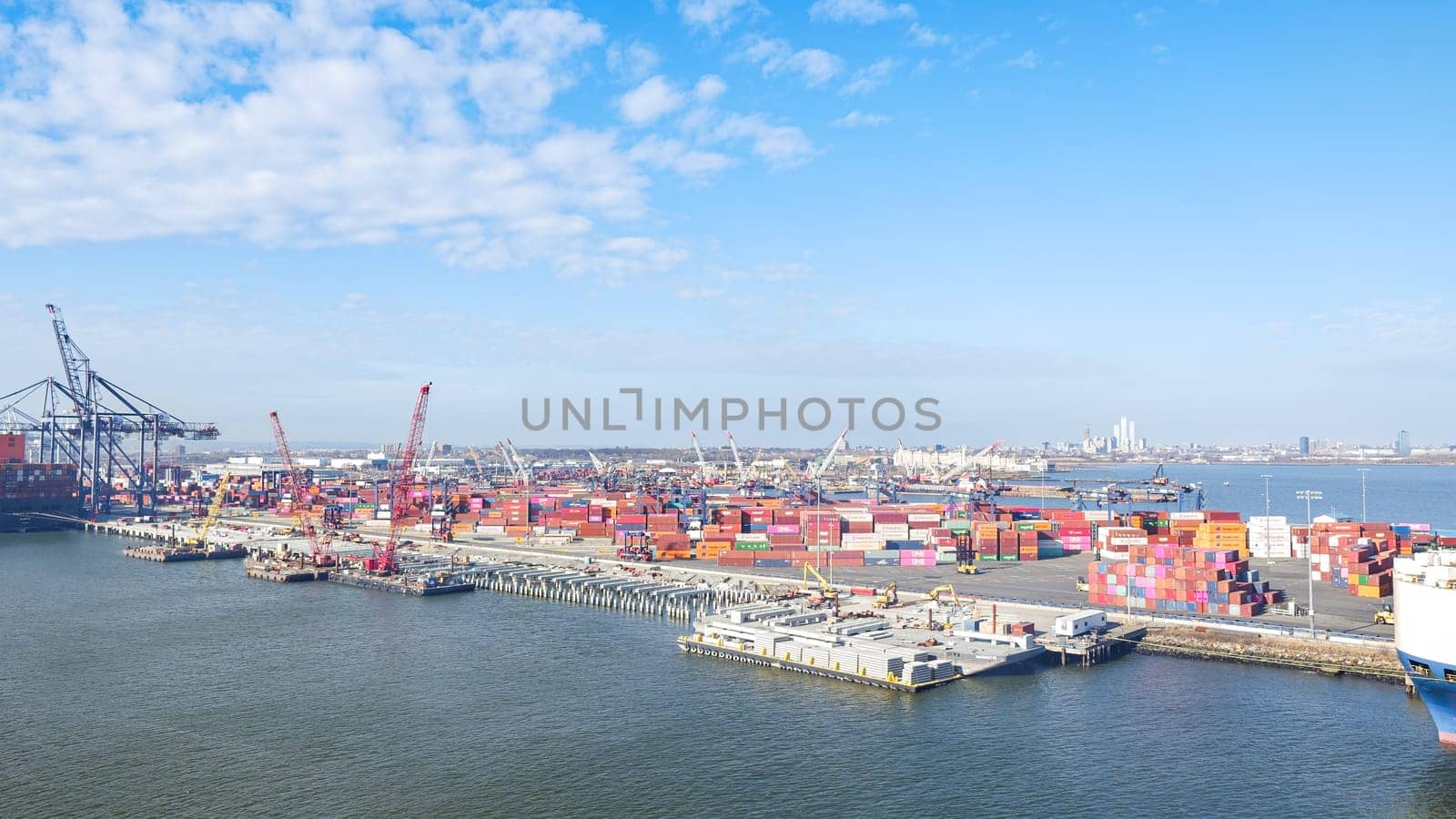 New York NY USA - 09.02.2024: Cargo containers stacked in a shipping yard near the sea with a city in the background.