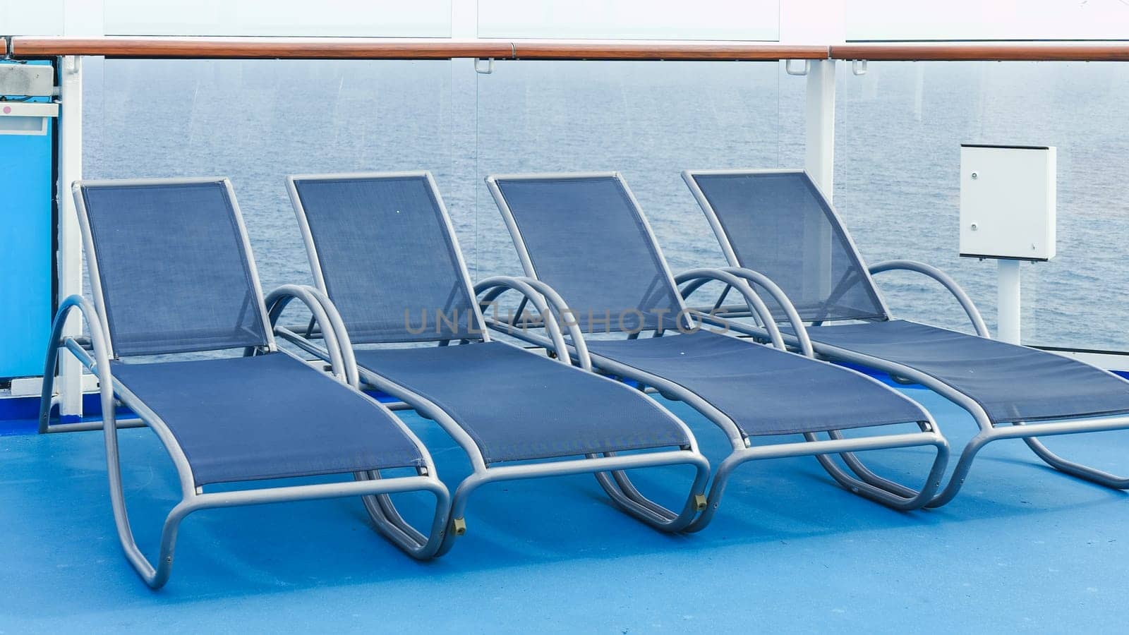 A serene view of blue deck chairs perfectly arranged in neat rows on a luxurious cruise ship deck