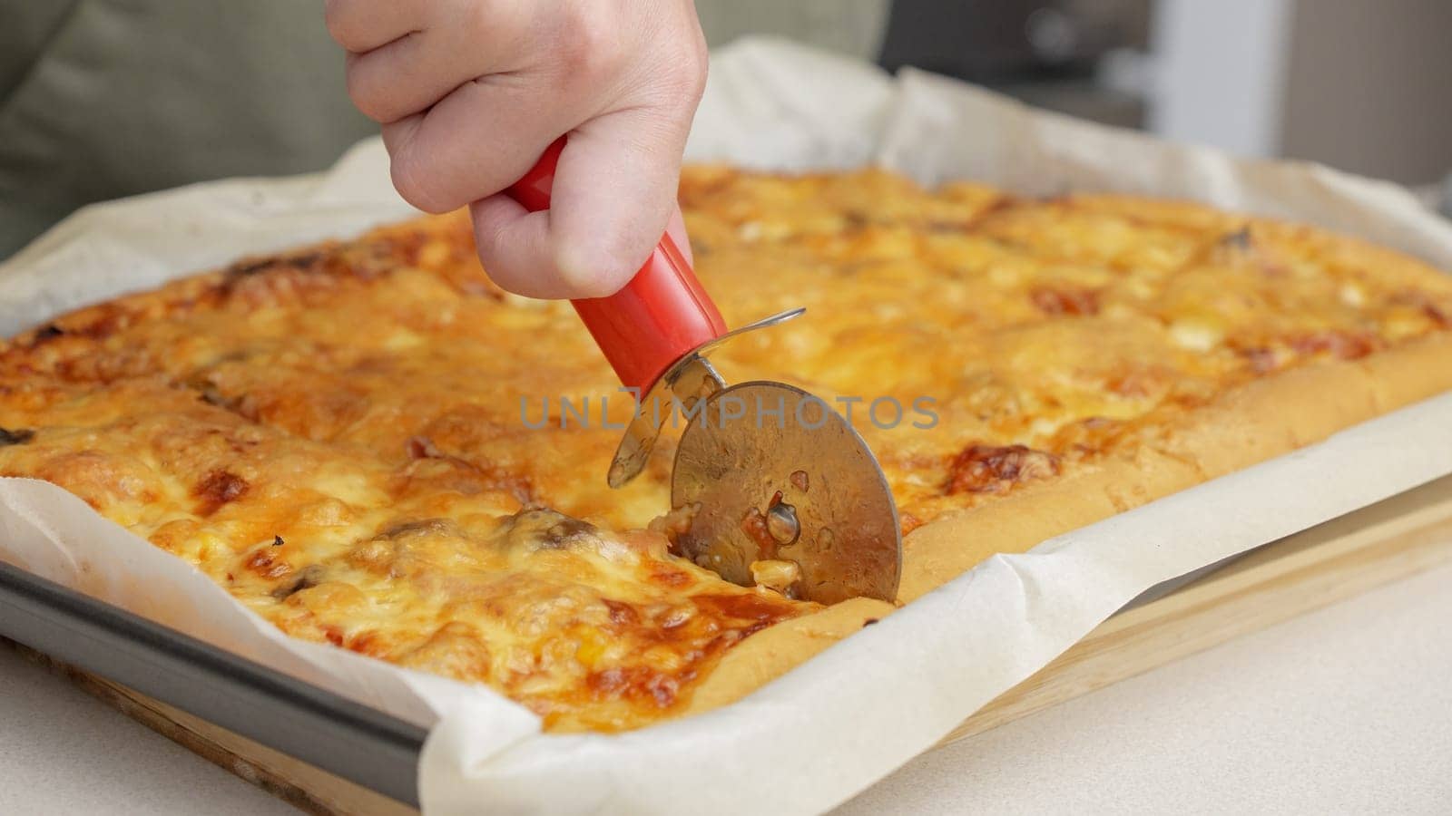 Cutting pizza with a round cutter knife. Close-up of delicious pizza being cut into pieces. Slow motion slicing a pizza into multiple slices with a cutter